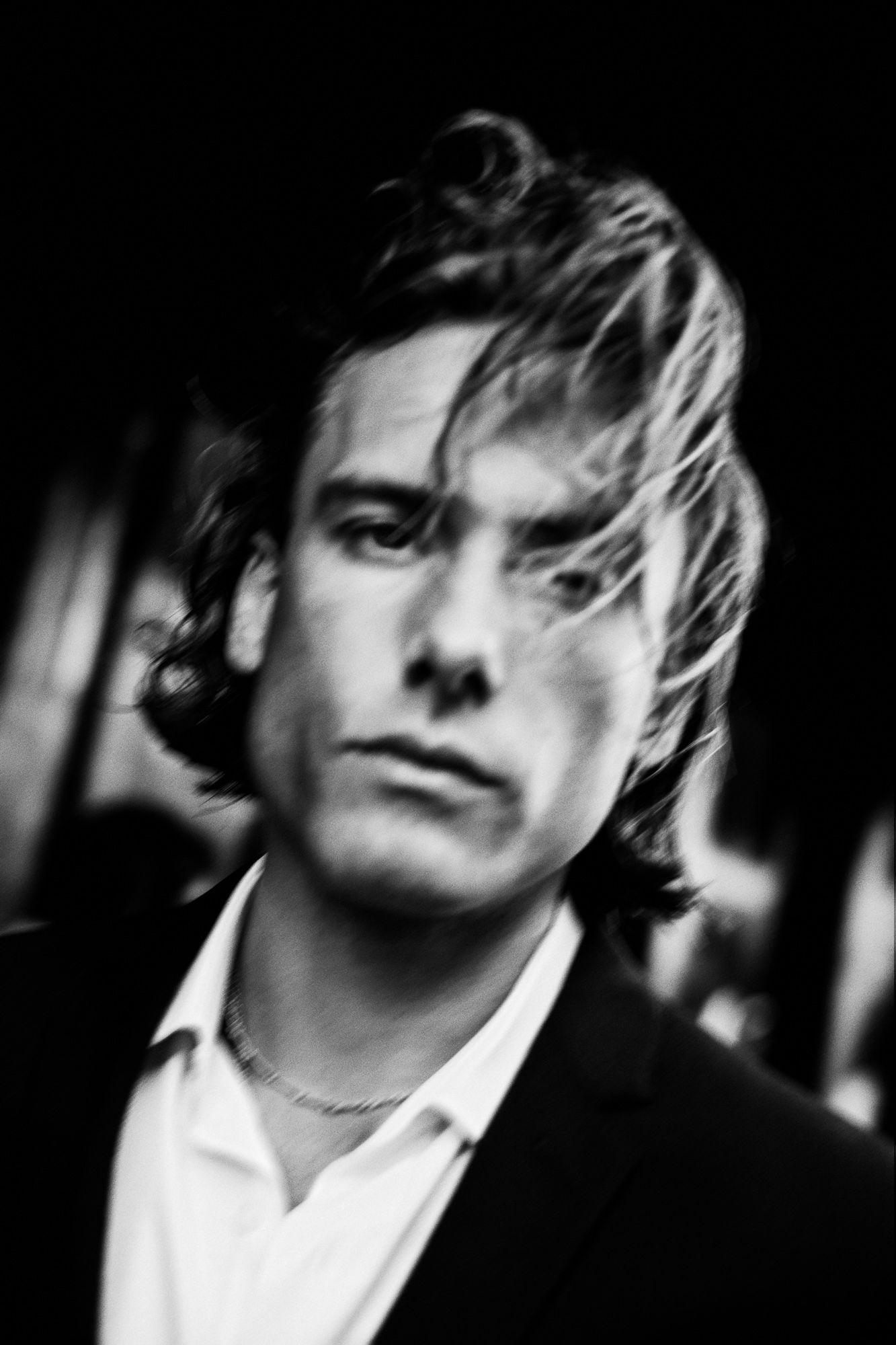 Dramatic black and white portrait with moody lighting and tousled hair.