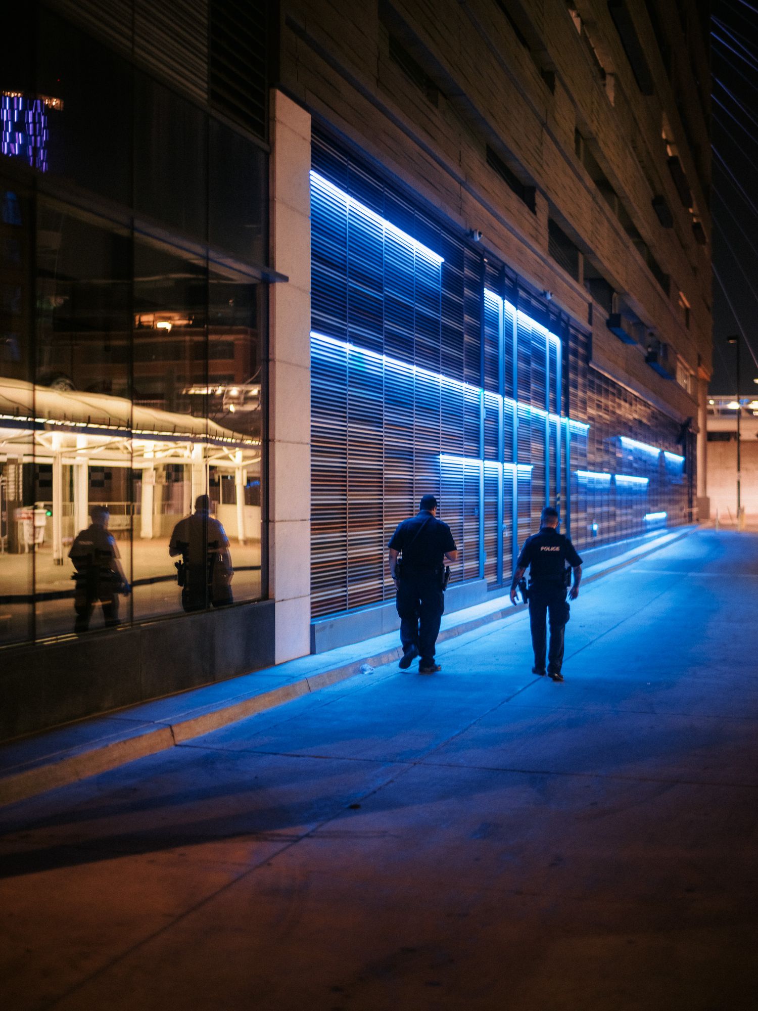 People walking through a corridor with striking blue neon lighting effects.
