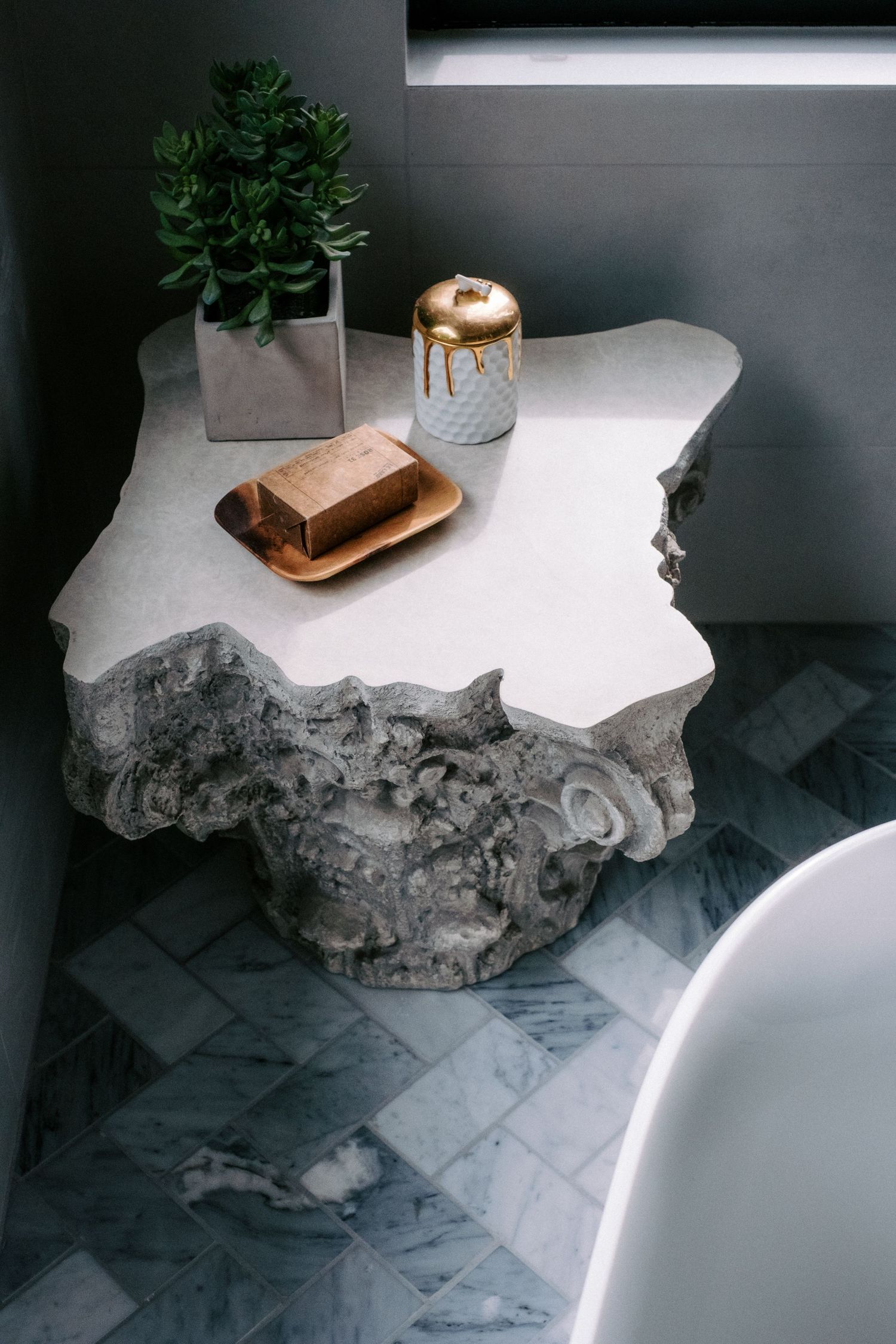 Rustic stone and marble bathroom counter with decorative wooden box.