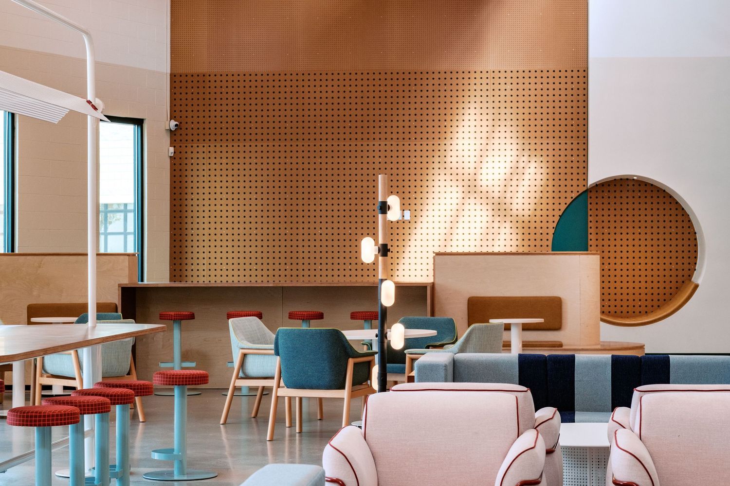 Contemporary cafe interior with perforated wood panels and pendant lighting creating a warm atmosphere.