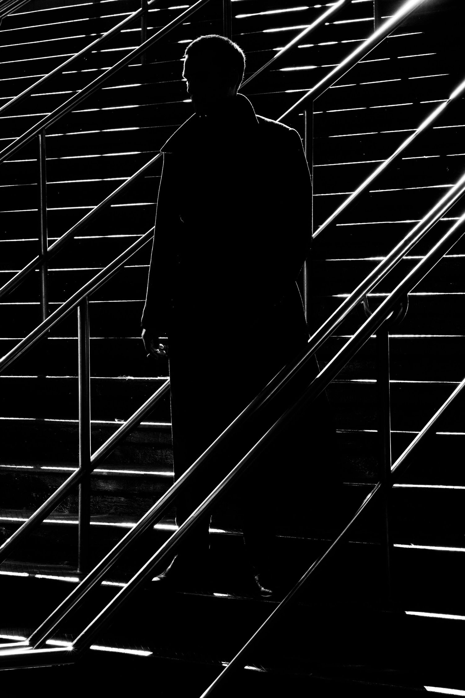 Silhouetted figure stands in an empty parking lot at night with diagonal white lines creating dramatic patterns.