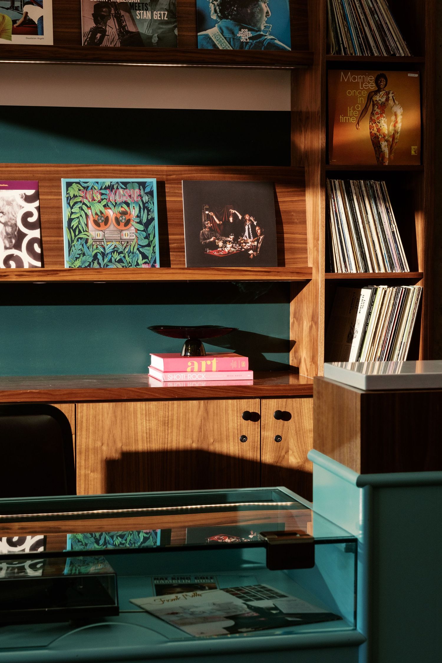 Stylish built-in shelving unit with turquoise accents displaying vinyl records and books.