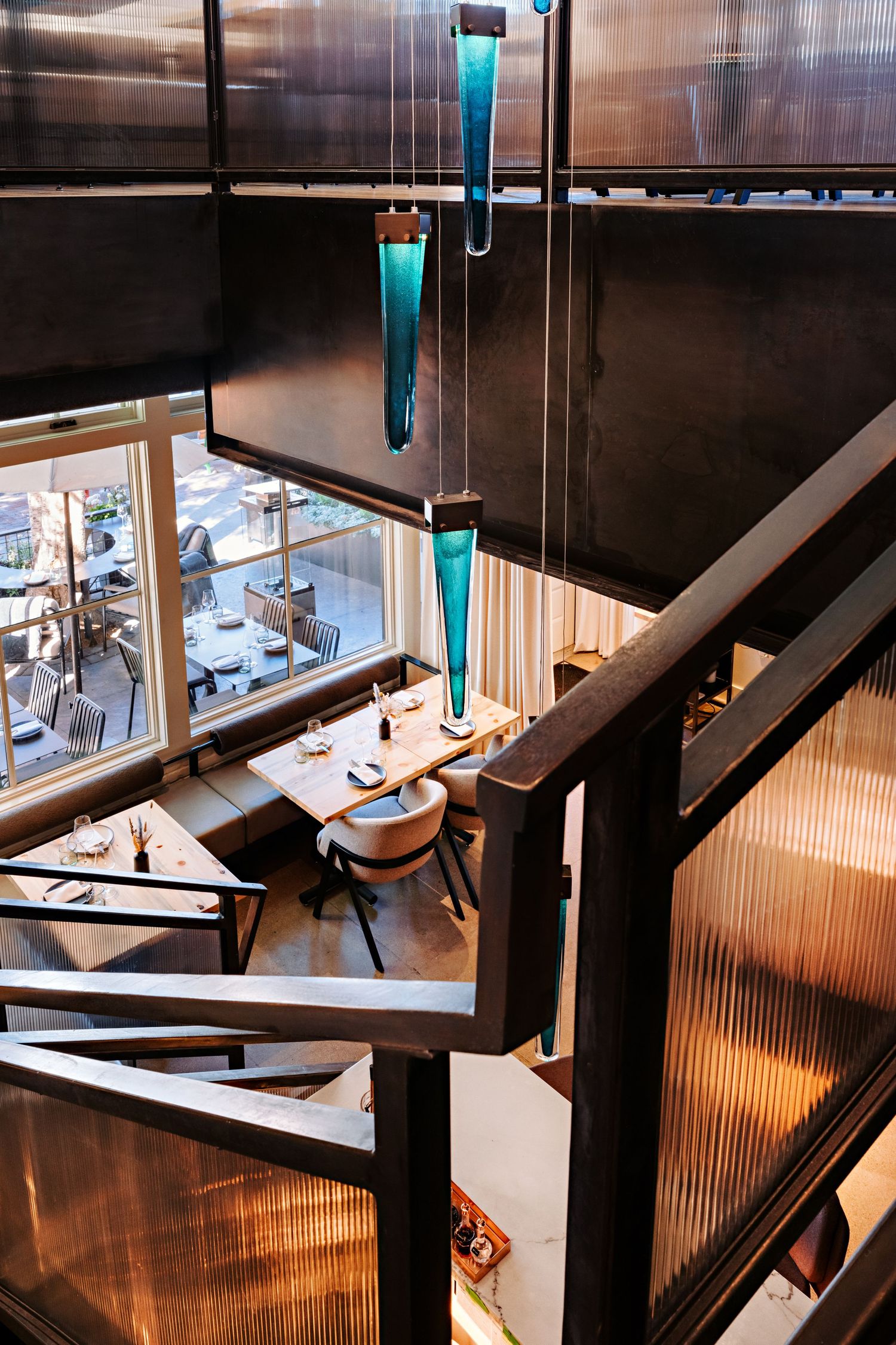 Elegant dining area with turquoise pendant lights and natural sunlight streaming through windows.