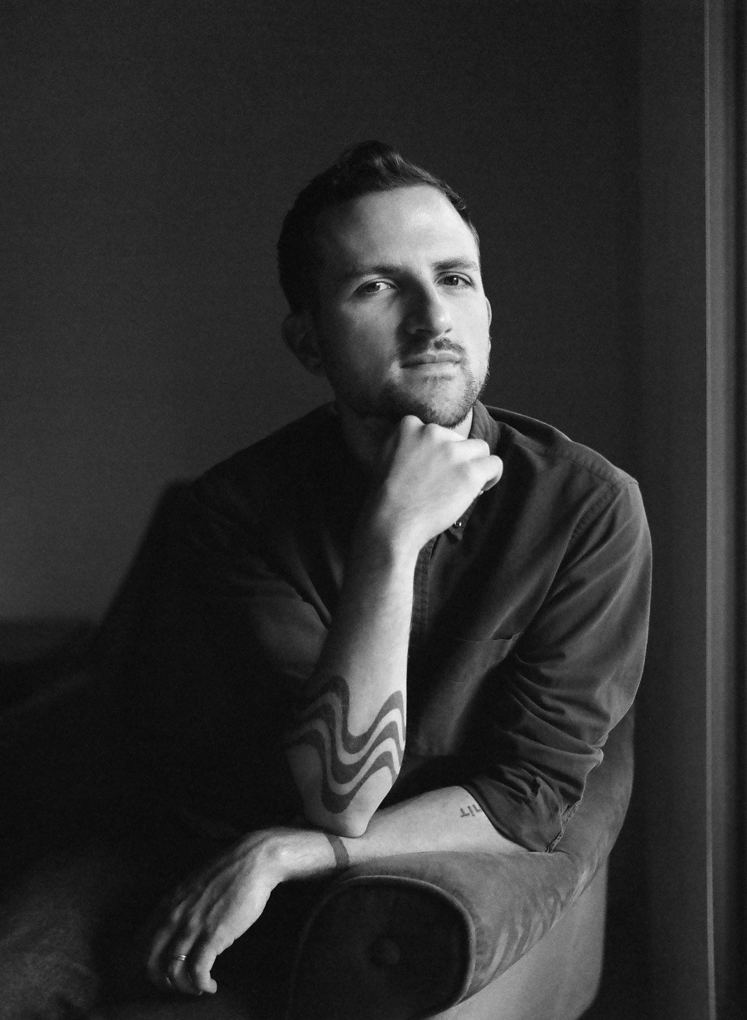 Dramatic black and white portrait series showing contemplative poses against dark background.