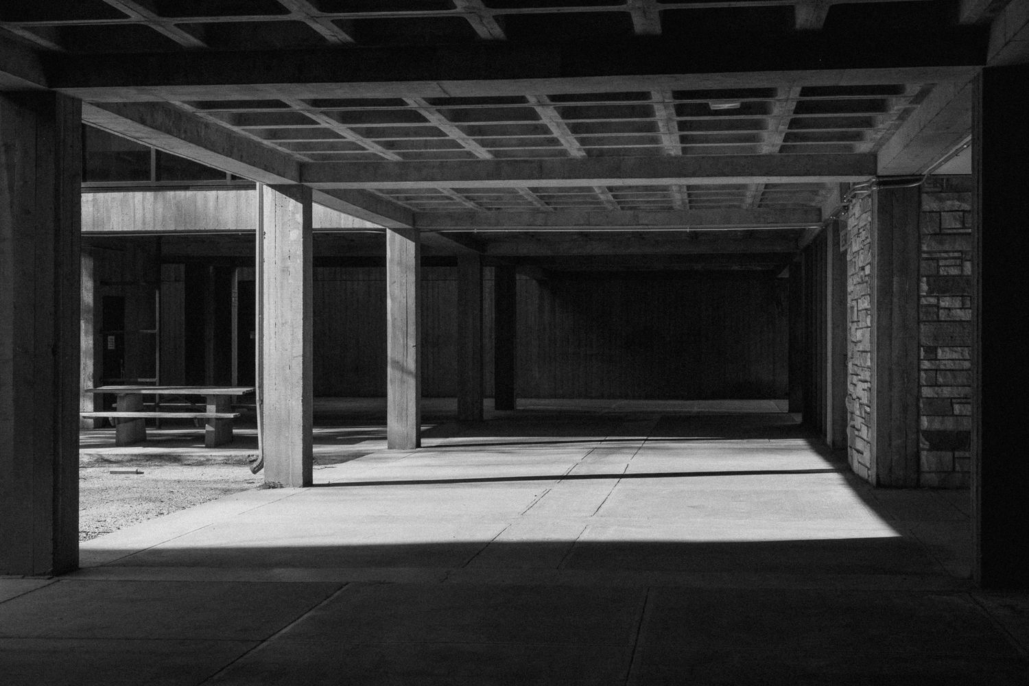 Industrial concrete interior with dramatic lighting and exposed ceiling beams.