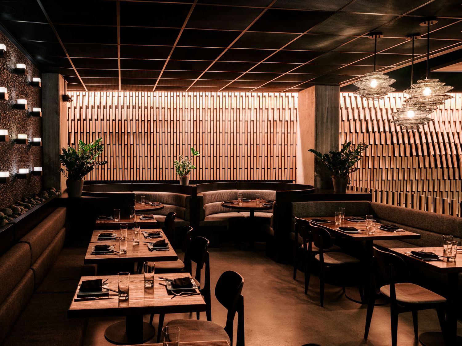 Modern restaurant dining area with wooden lattice wall feature and ambient lighting.