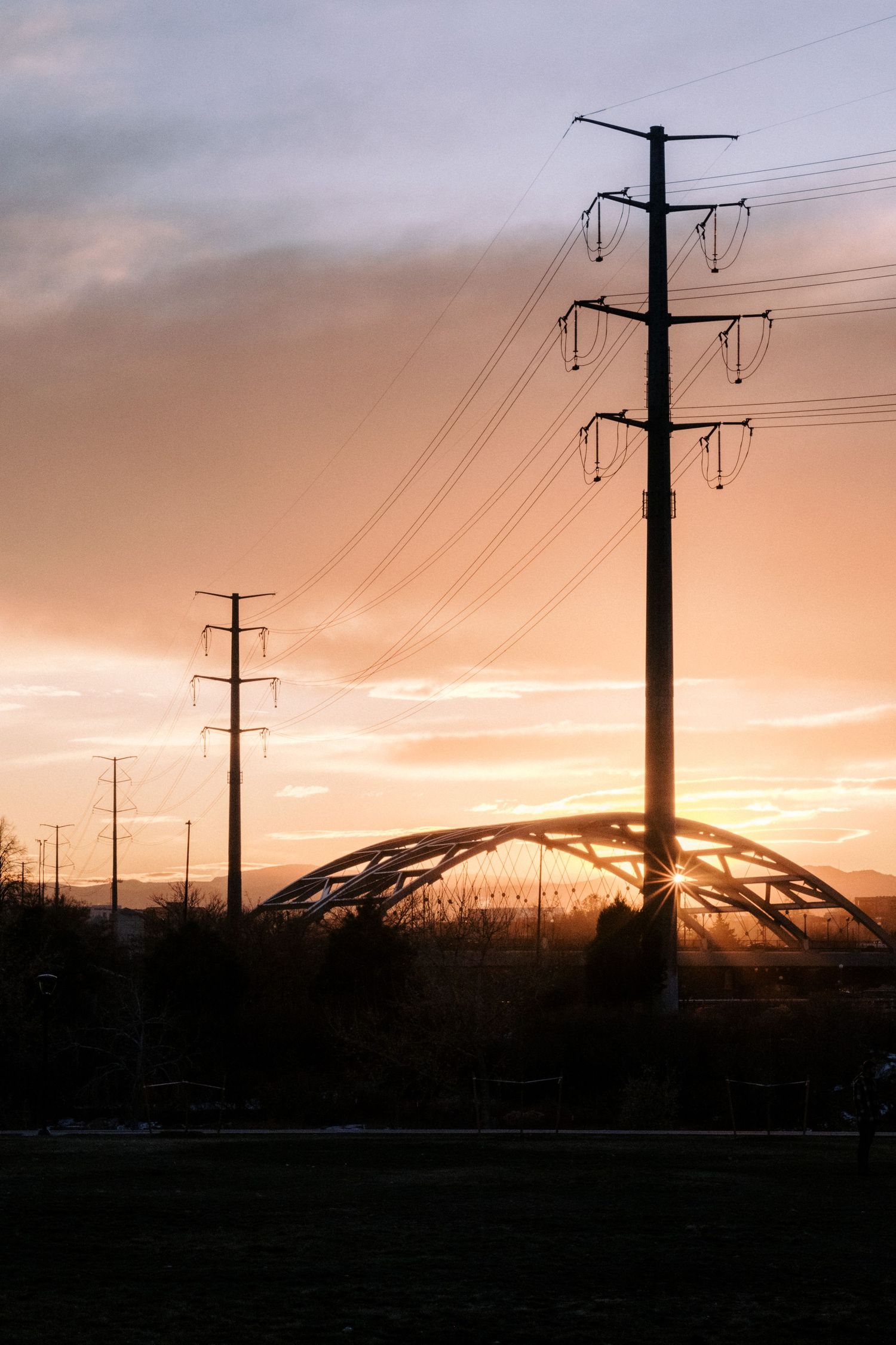 Power lines silhouetted against a dramatic orange sunset sky.