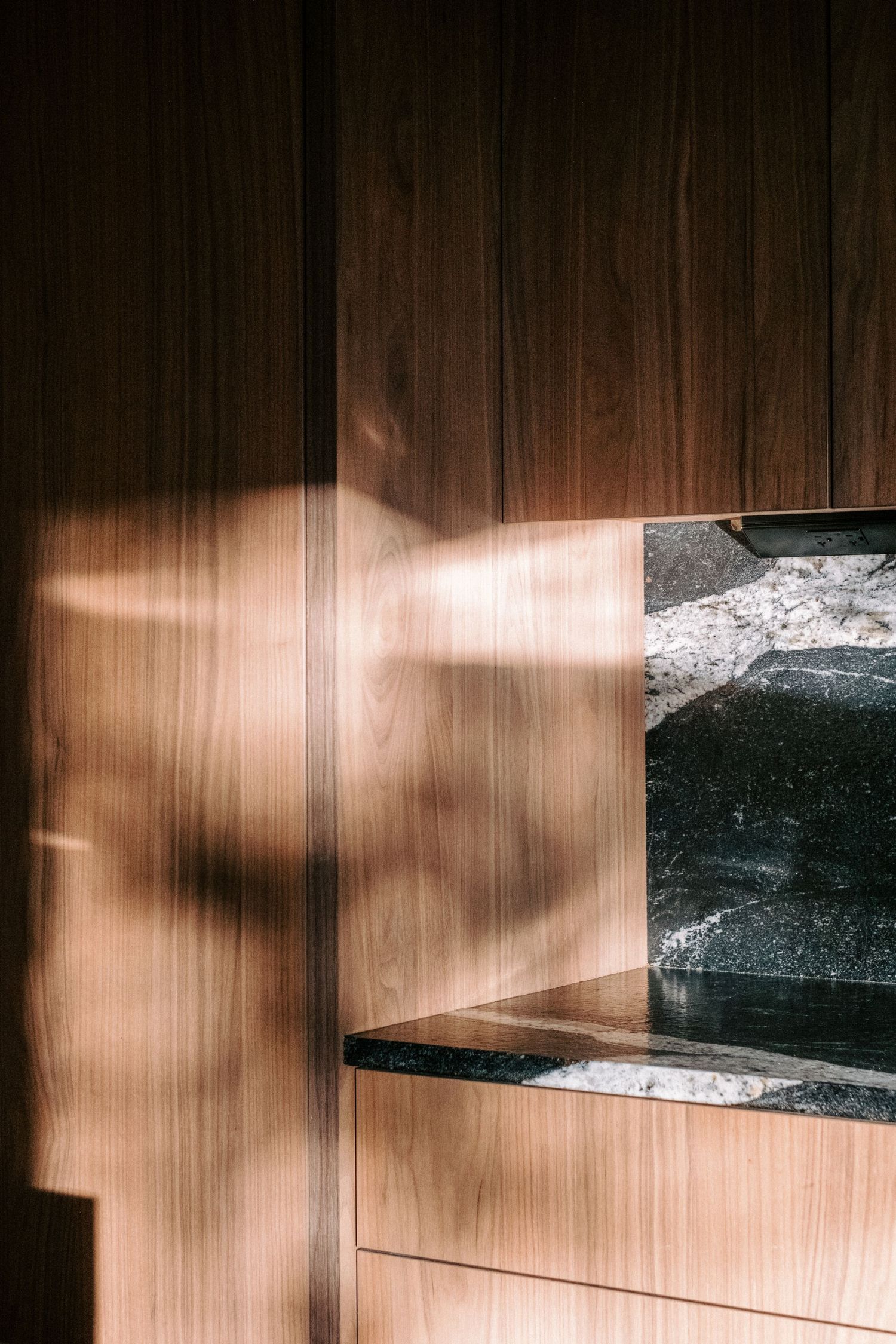 Sunlight casting dramatic shadows on wooden paneled wall with stone accent.