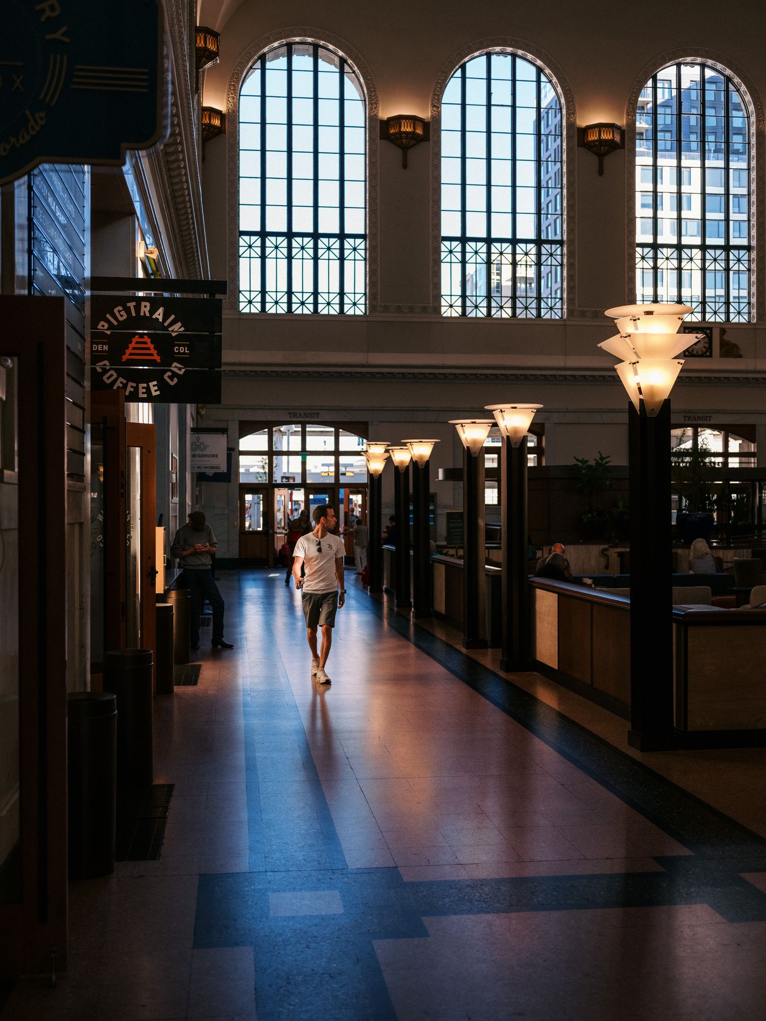Historic hallway with arched windows and pendant lights creating dramatic shadows.