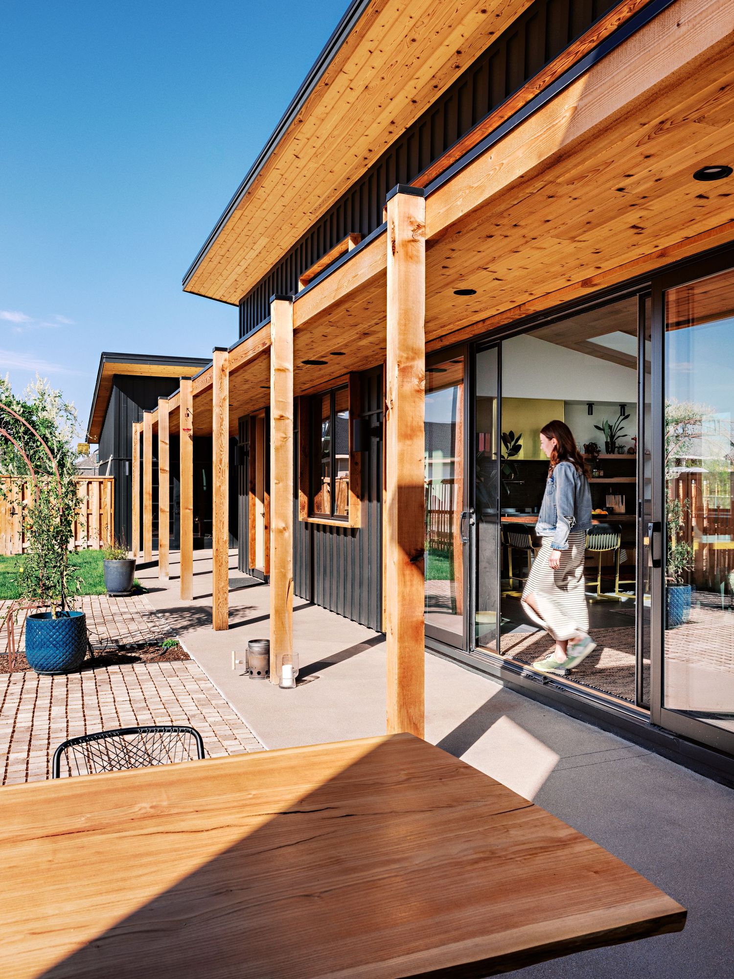 Expansive wooden deck with overhanging roof and glass sliding doors leading to interior space.