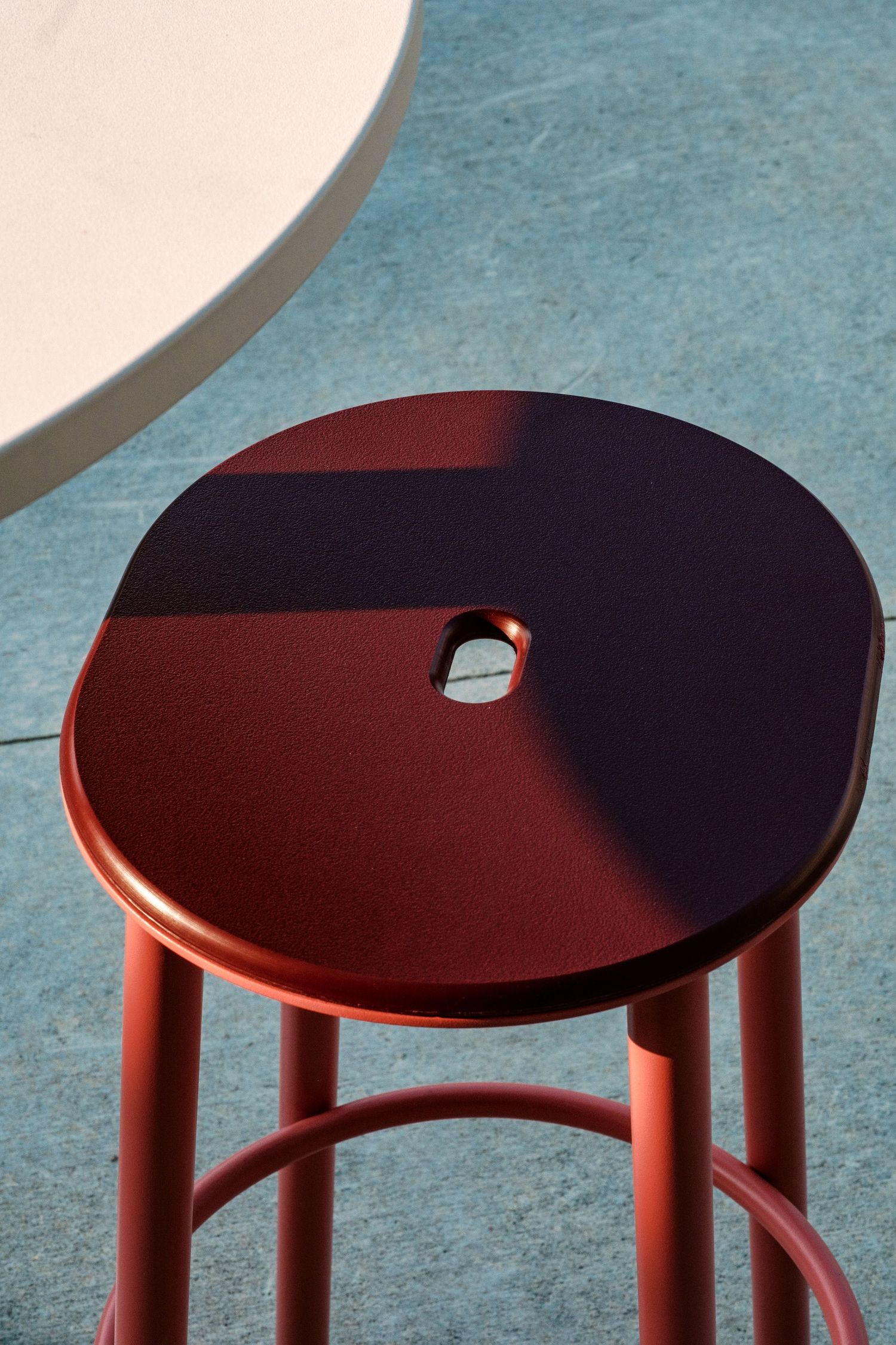 Close-up of a red circular stool top showing clean geometric design and shadow detail.