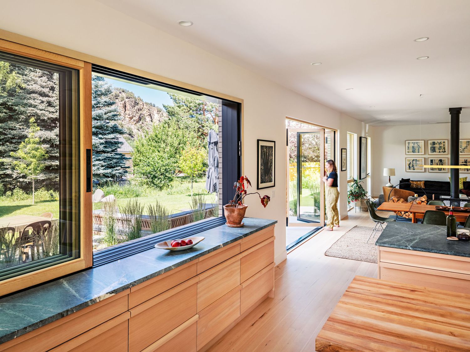 Long built-in window seat with panoramic views of outdoor landscape and natural wood finishes.