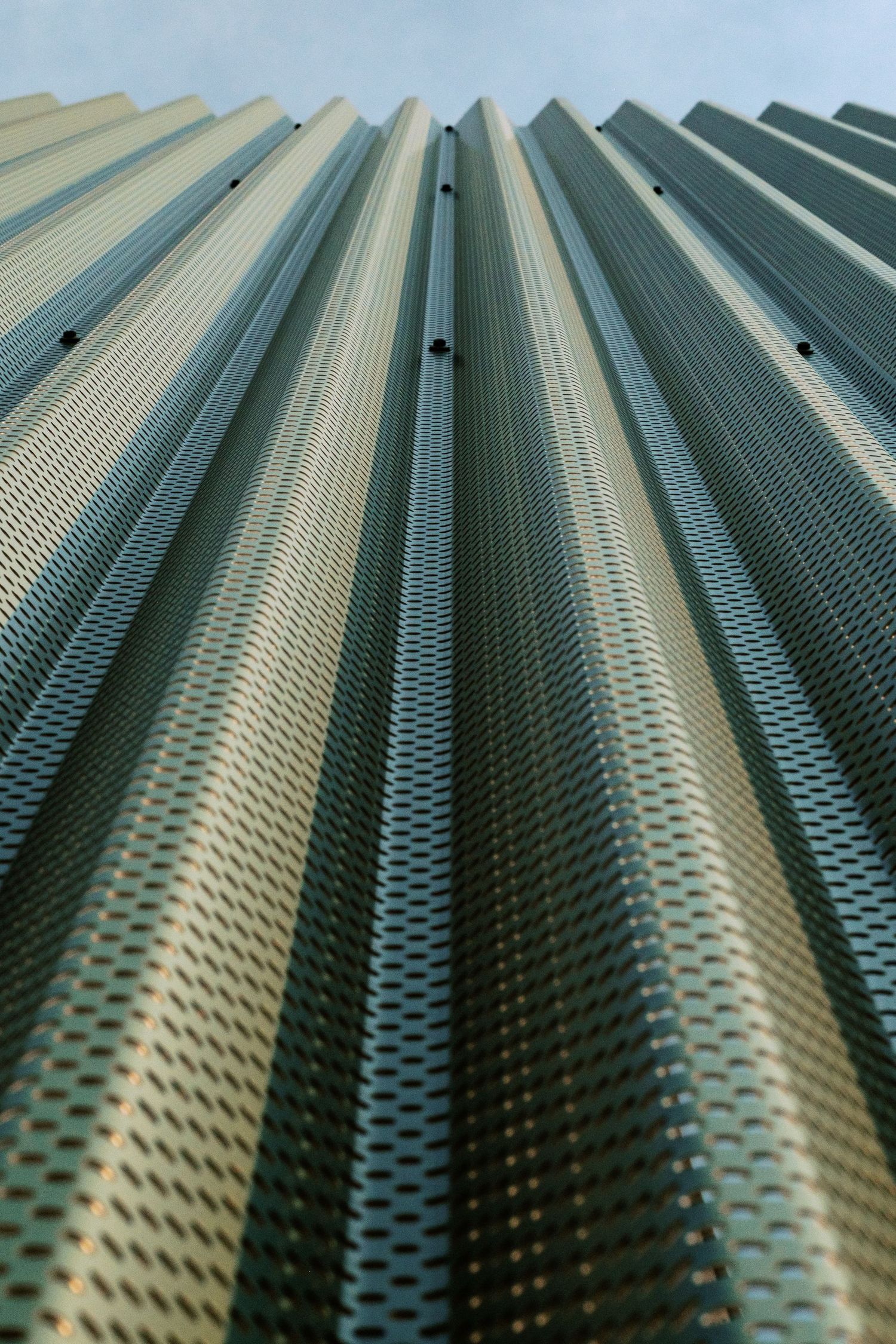 Abstract pattern of metallic corrugated panels creating repetitive diagonal lines and shadows.