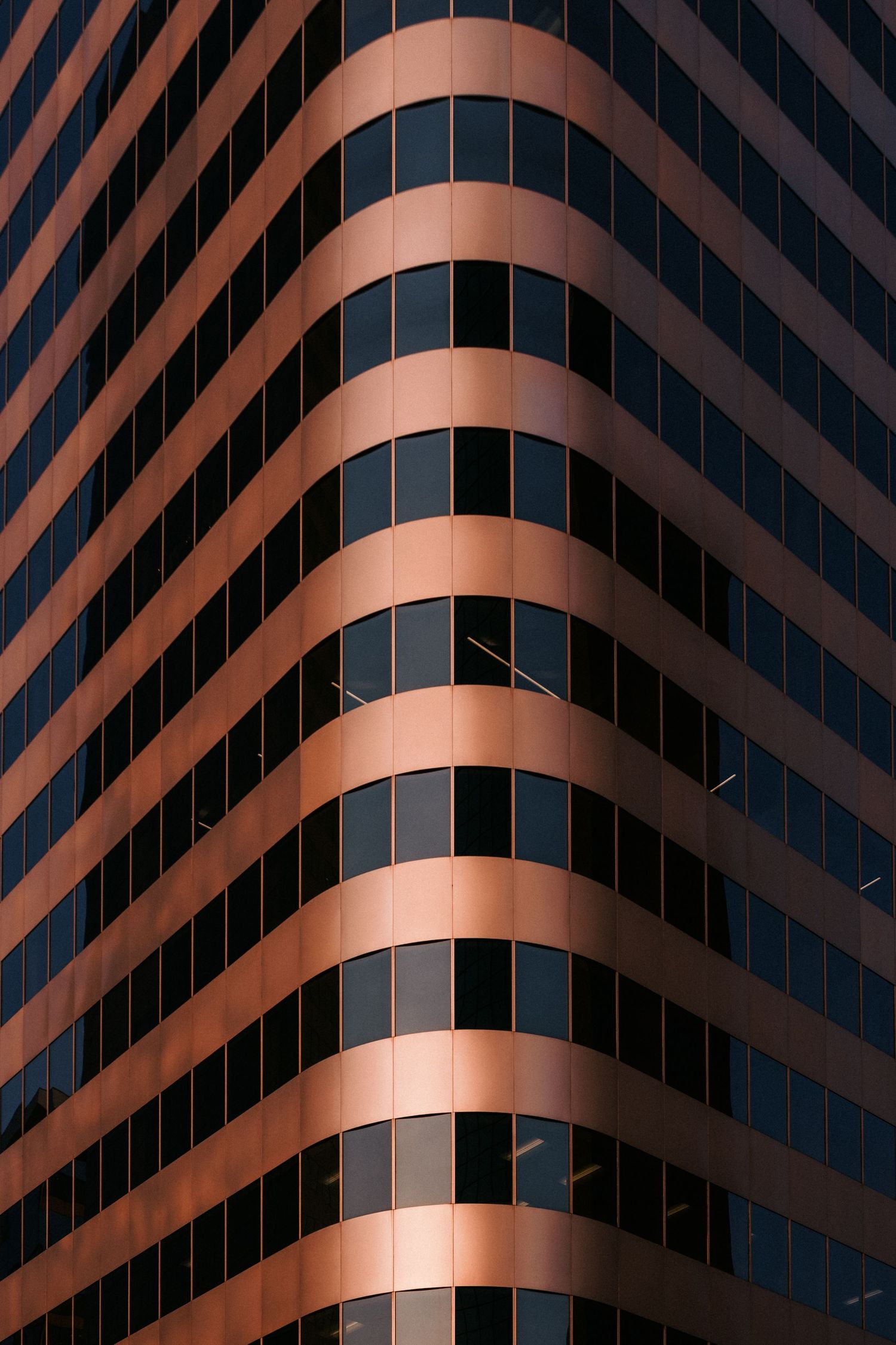 Modern office building facade with curved copper-colored architectural details.