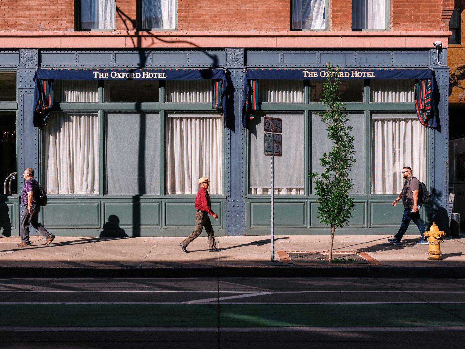 Street scene with red brick building and pedestrians walking past storefronts.