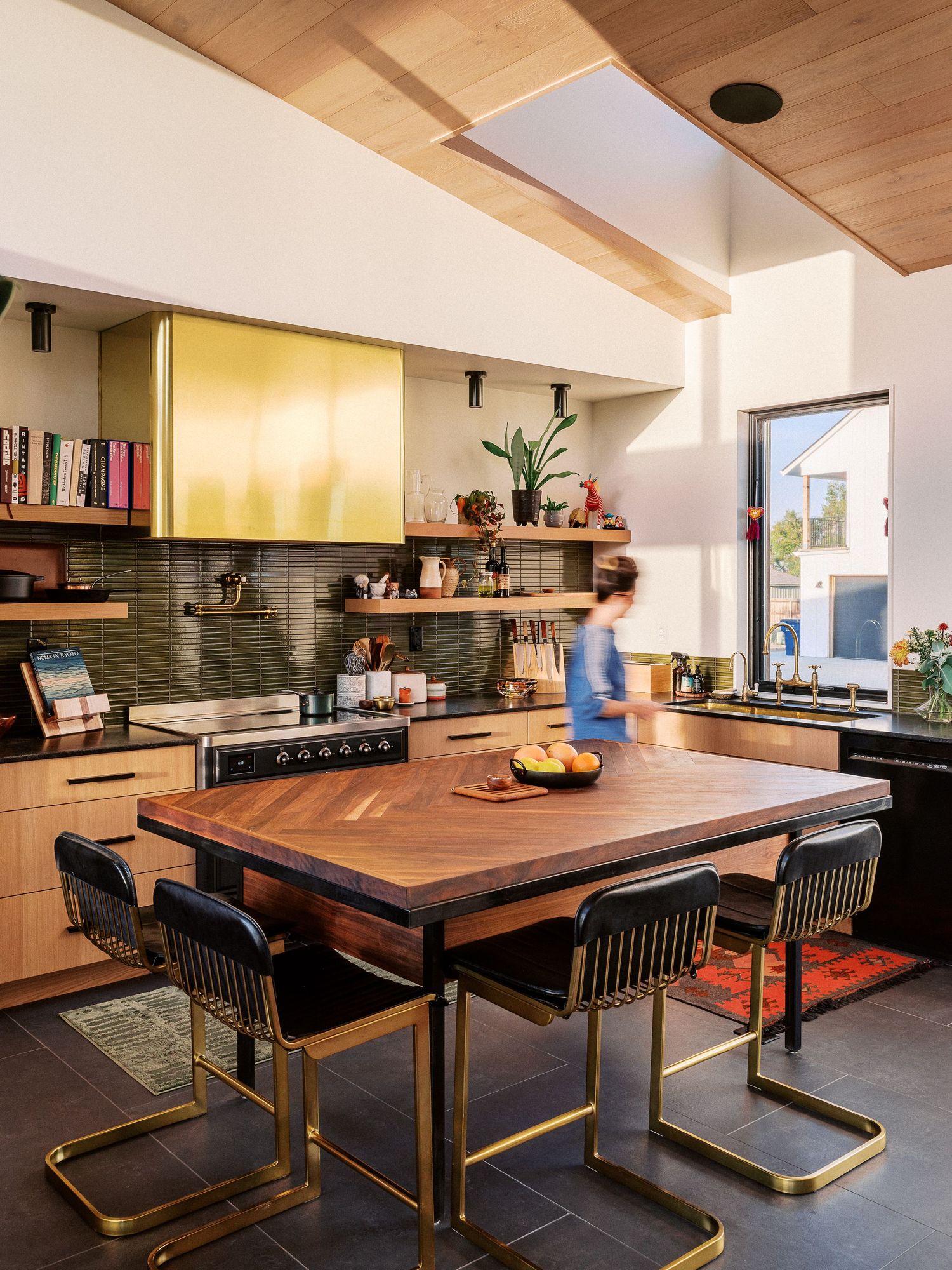Modern dining area featuring a dark wood table with black chairs and brass accents in an open concept kitchen space.
