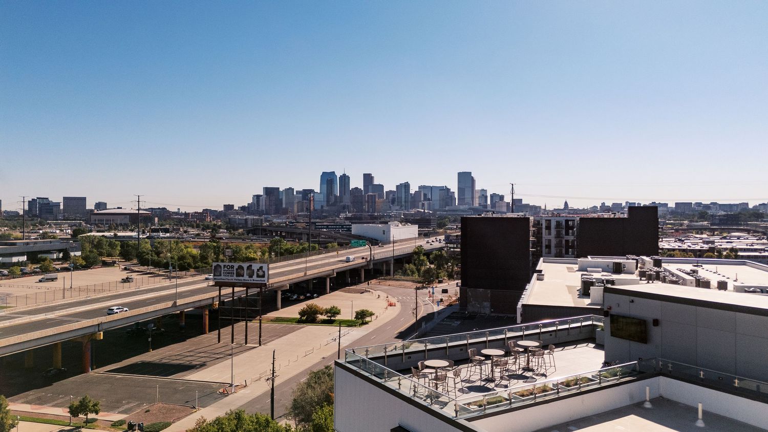 Panoramic view of downtown Denver skyline with highway and buildings in foreground.