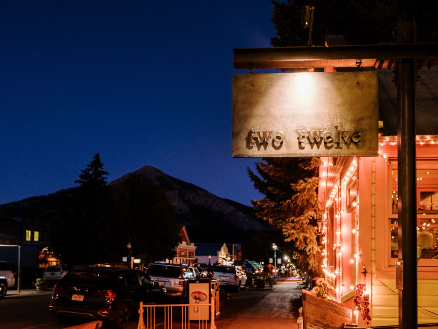 Night scene of mountain town with glowing neon signs and street lights.