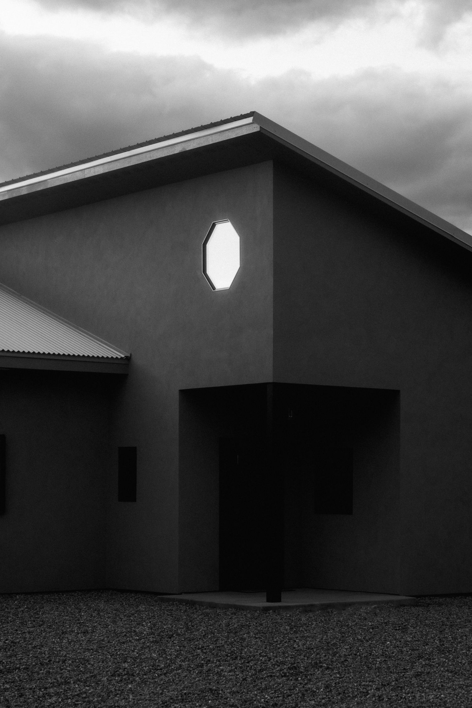 Minimalist building exterior with octagonal window in black and white.