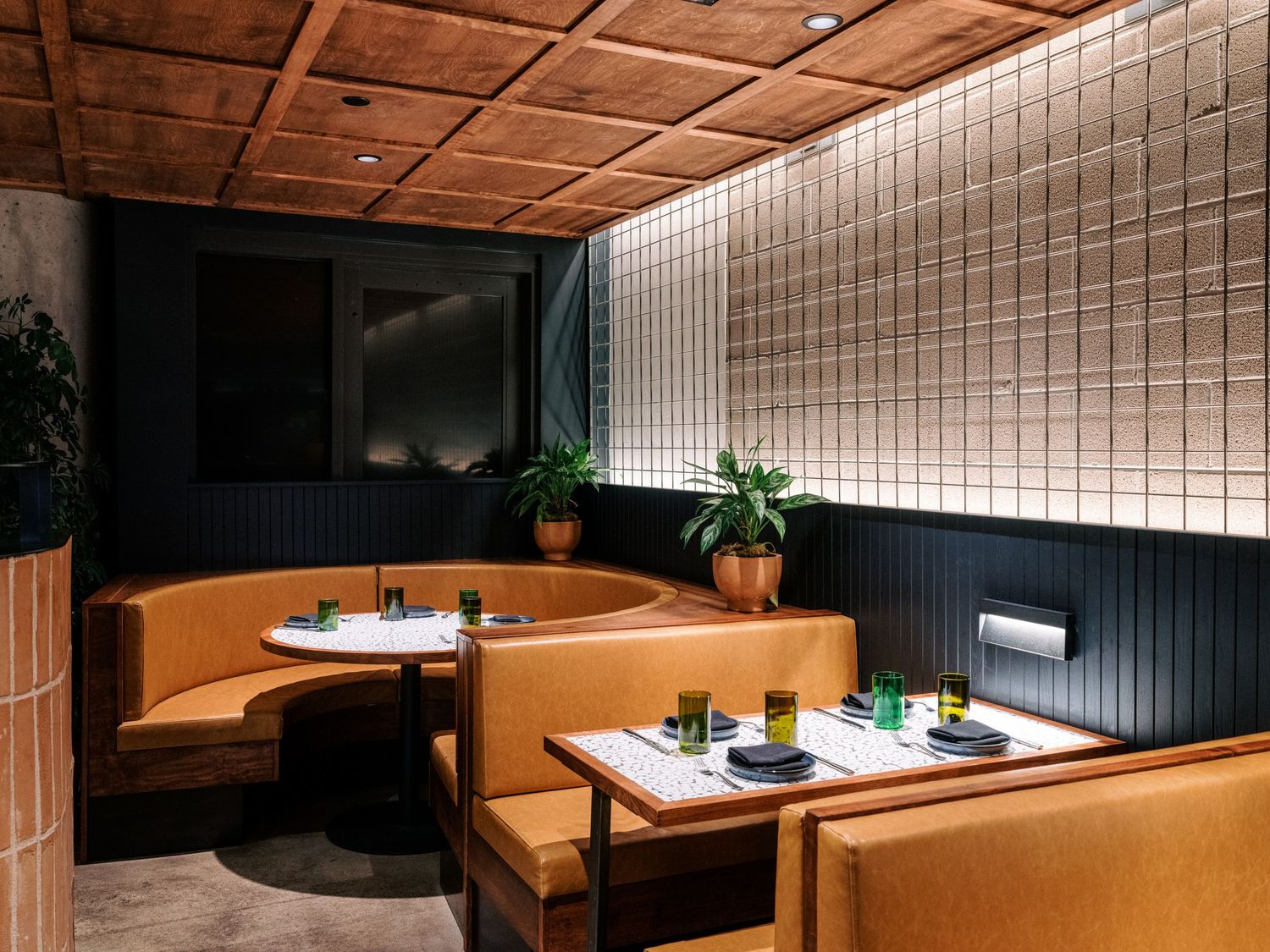 Contemporary restaurant interior with wooden ceiling panels and booth seating.