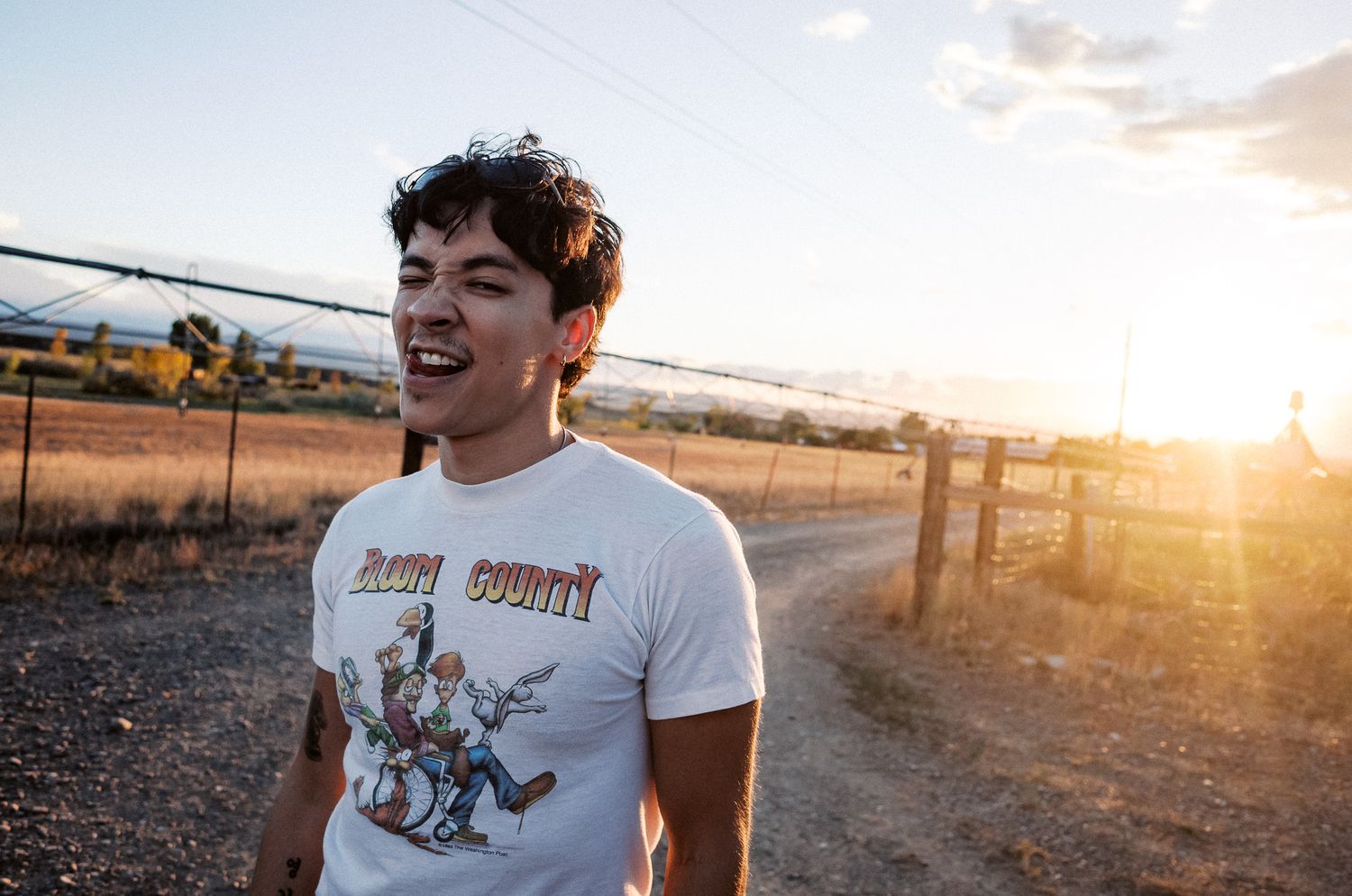 Person in white t-shirt walking along dirt path at golden sunset.