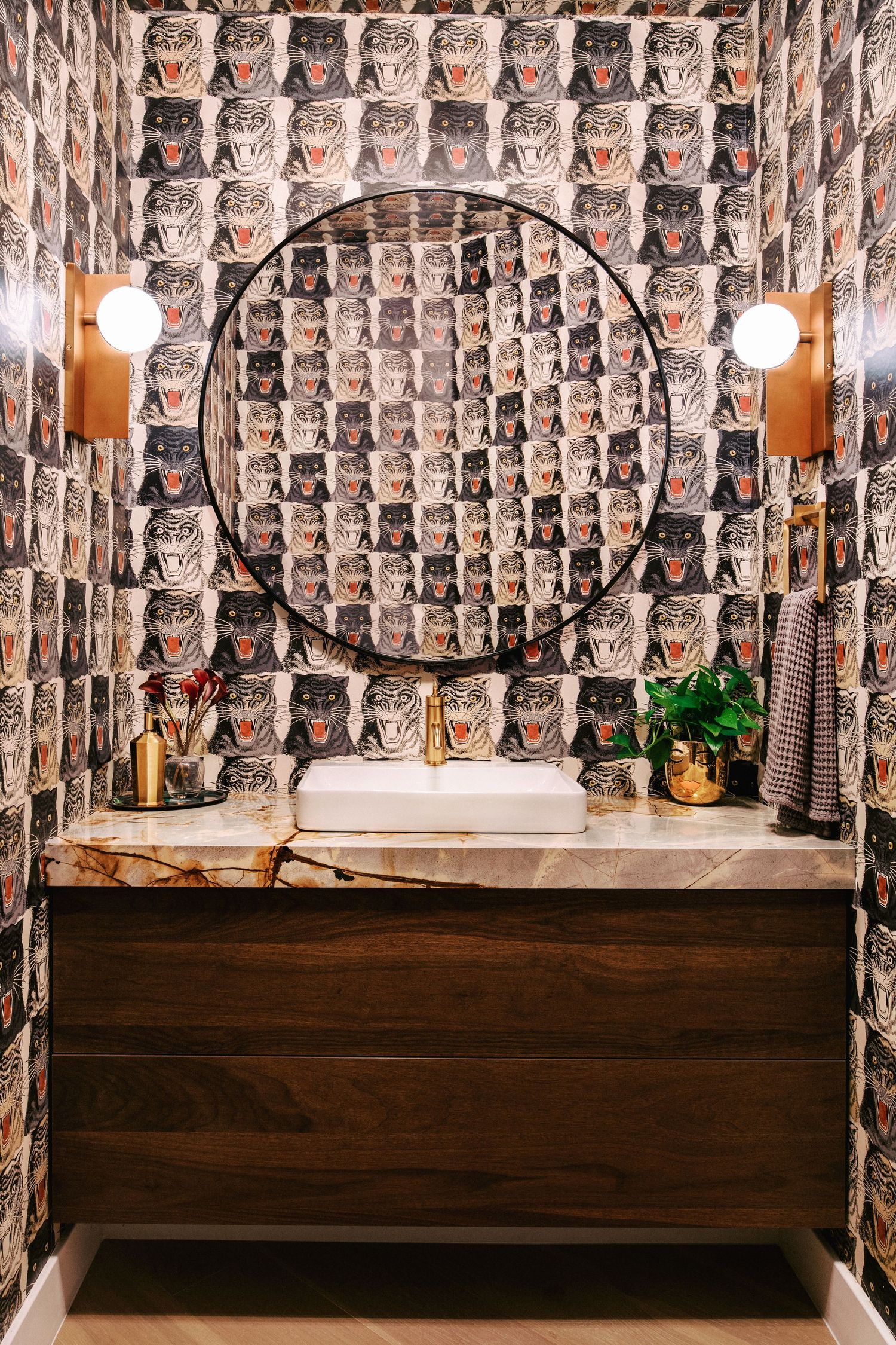 Unique bathroom vanity with circular mirror and patterned wallpaper featuring repeating owl designs.