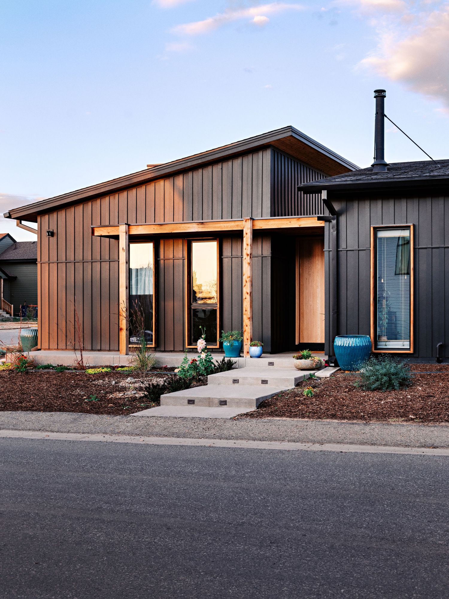 Contemporary black wooden house with warm lighting and minimalist design features.