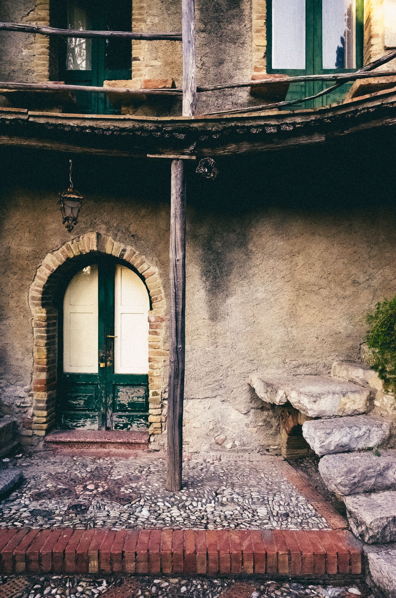 A series of abandoned stone buildings with arched doorways and windows showing deteriorating interior walls and debris.