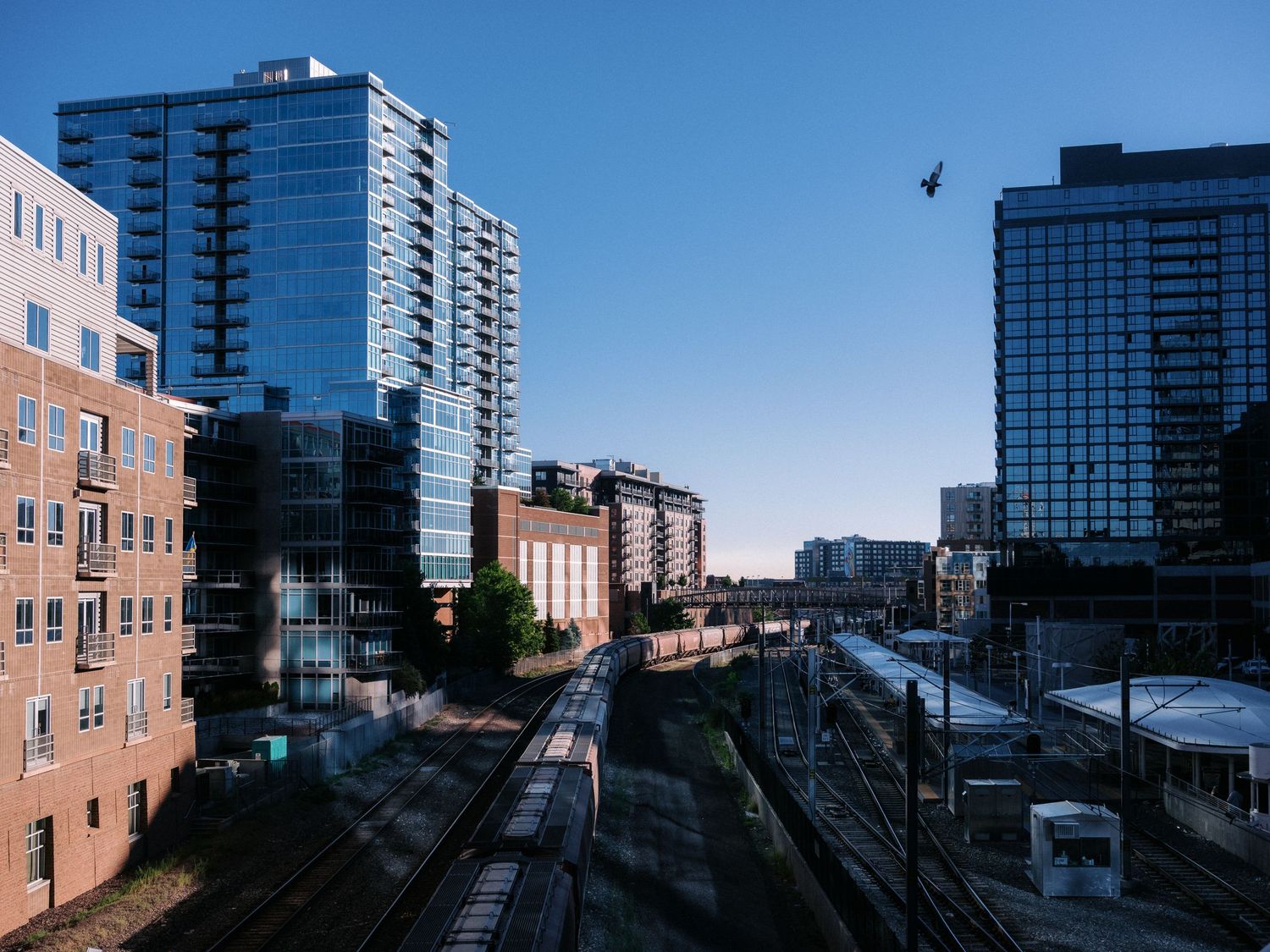 Urban cityscape panorama showing high-rise buildings against blue sky.