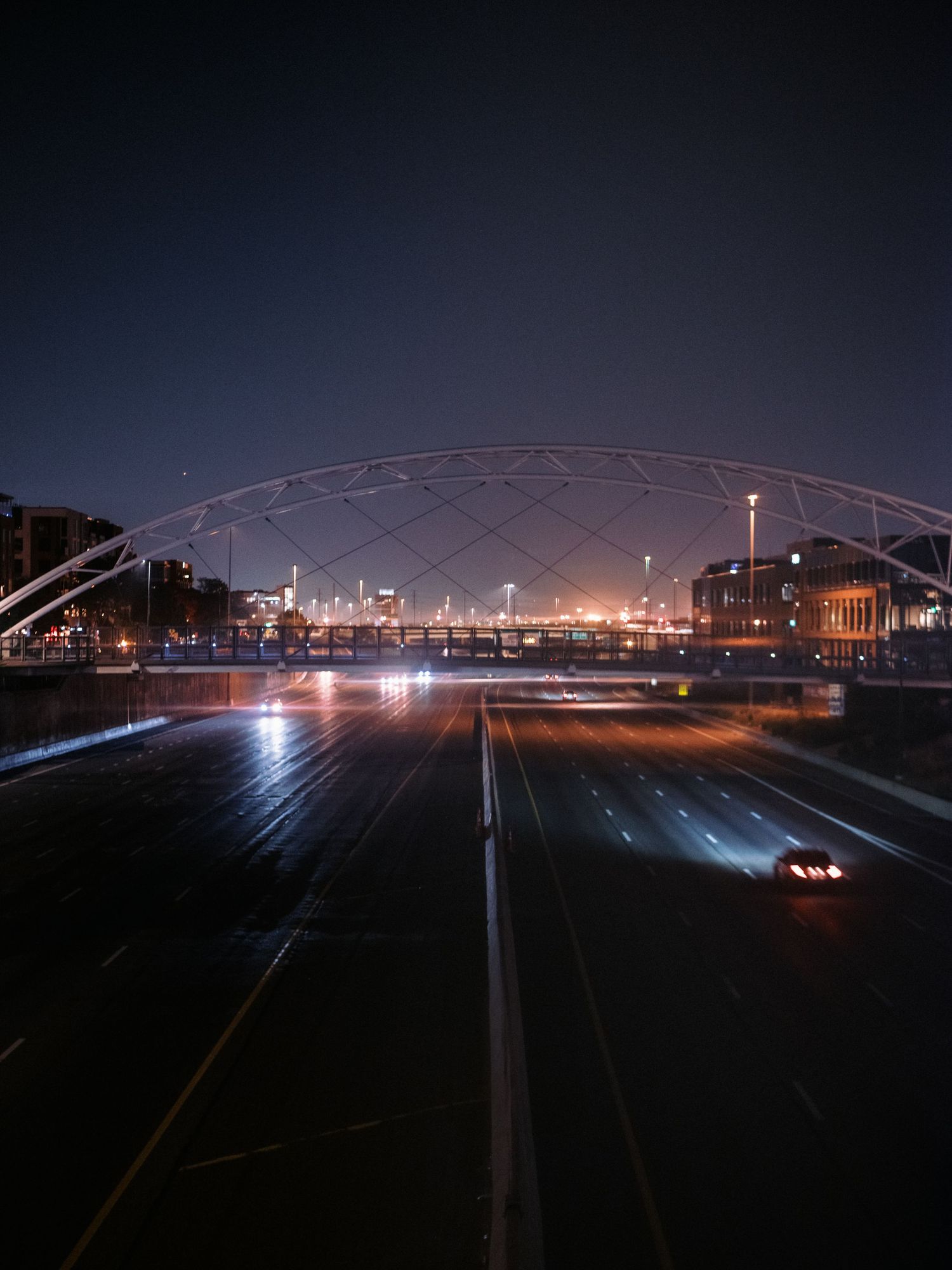 Dark nighttime panorama of train tracks and bridges illuminated by city lights.