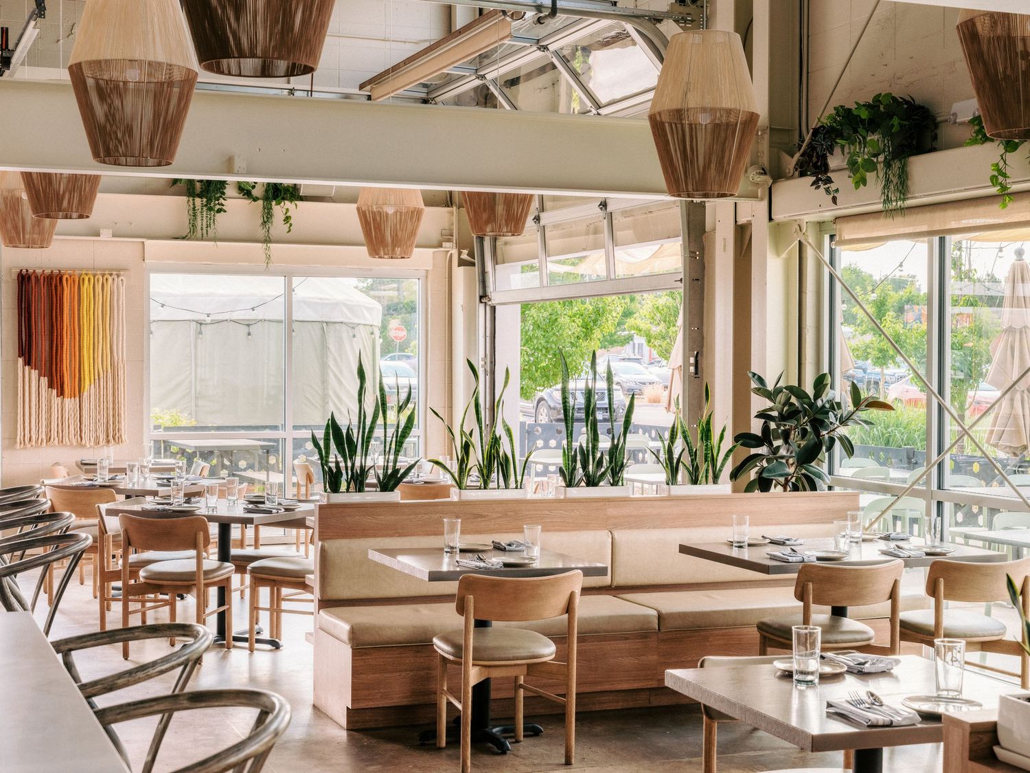 Modern restaurant interior with natural light, wooden furniture, and white walls.