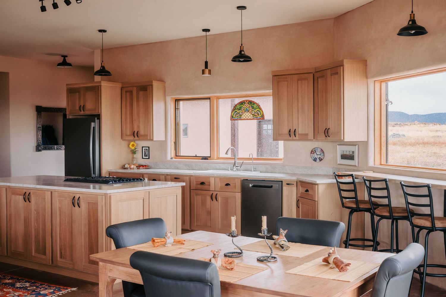 Modern kitchen and dining area with wooden cabinets and pendant lighting in an open floor plan.