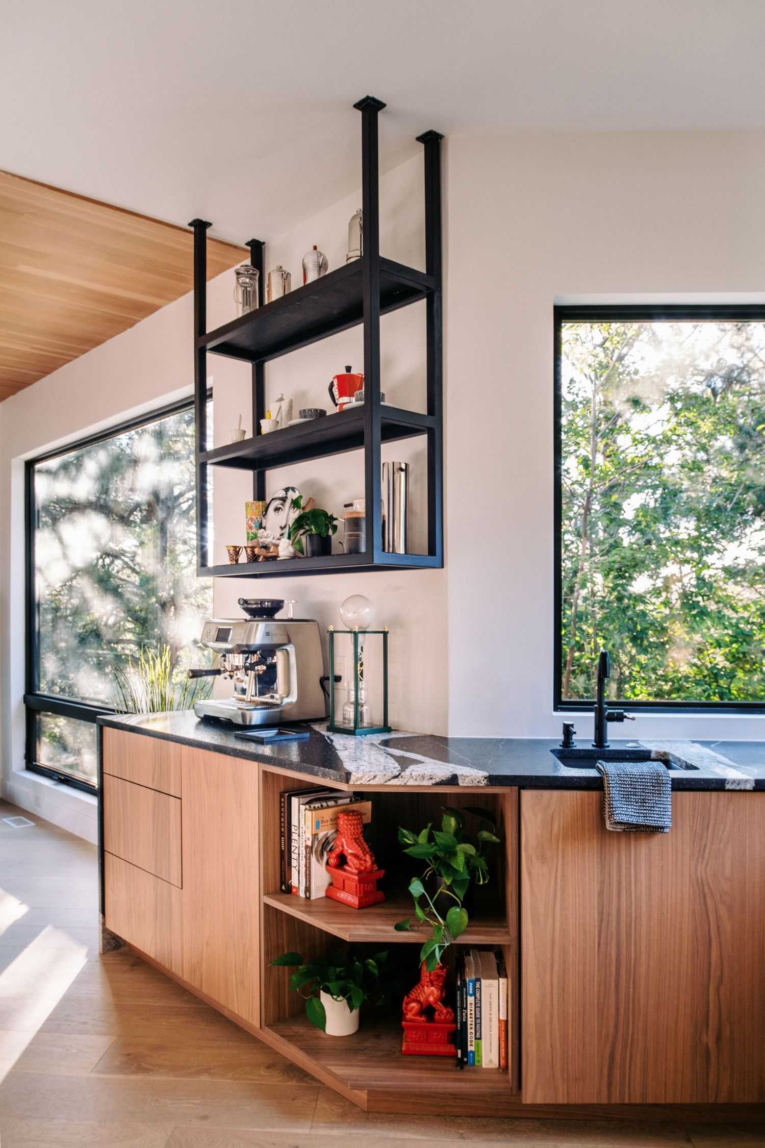 Kitchen storage featuring wooden cabinets and black floating shelves with decorative items.