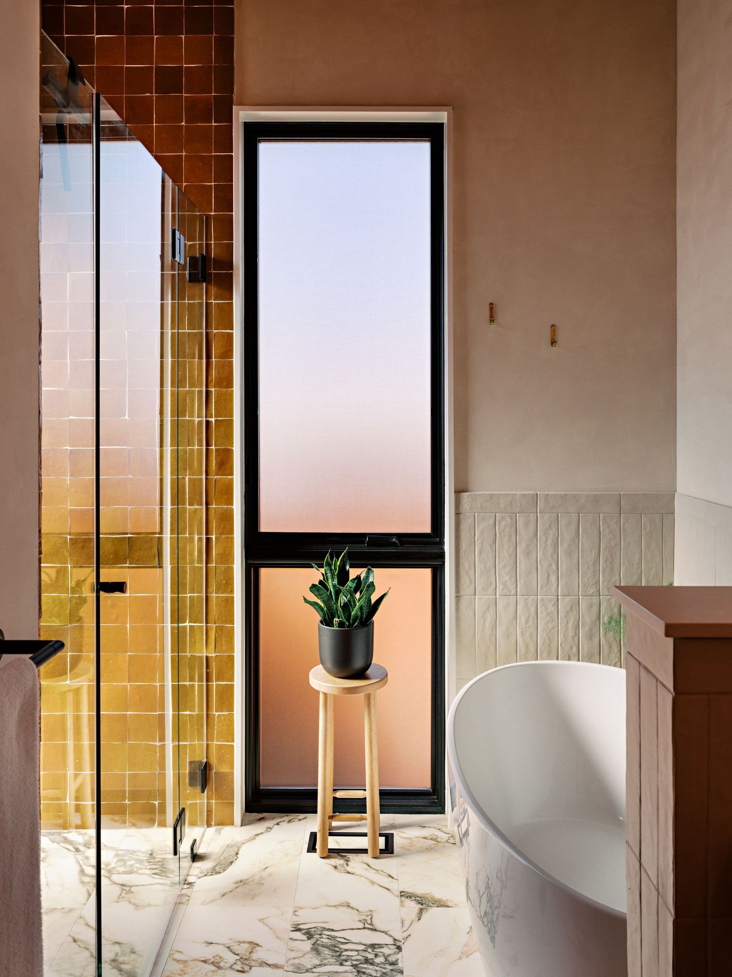 Modern bathroom with yellow tile accents, white walls, and windows offering sunset views.
