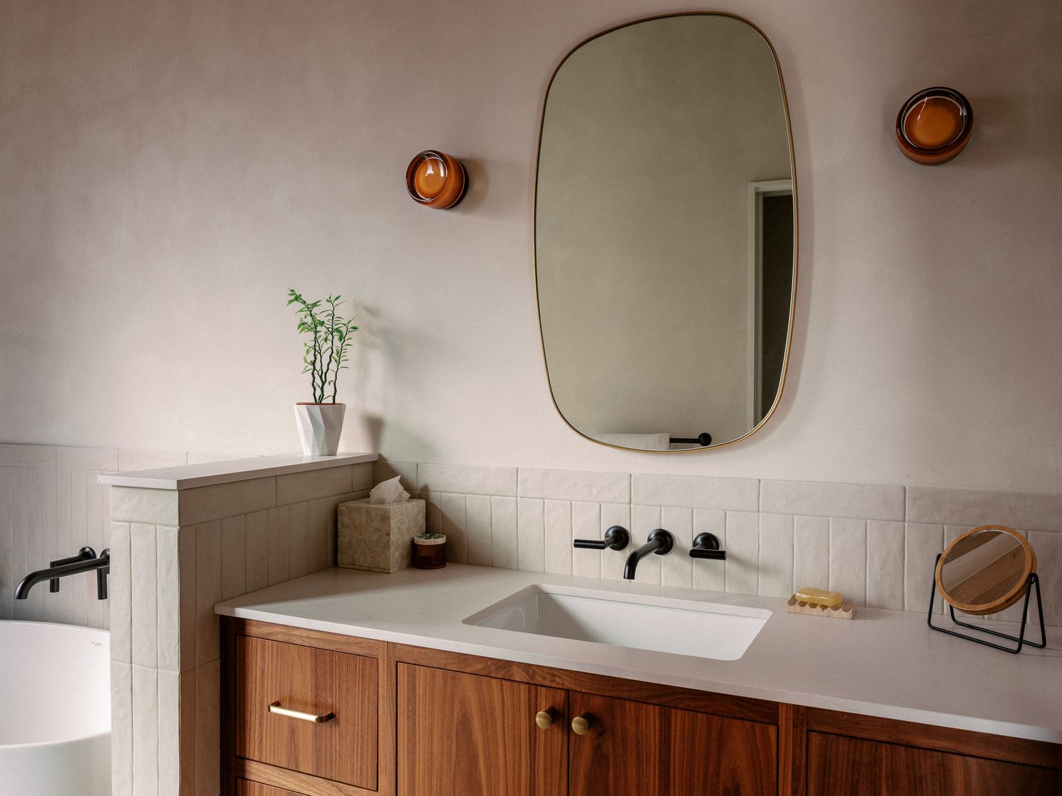 Modern minimalist bathroom interior with white walls, wooden accents and contemporary fixtures.
