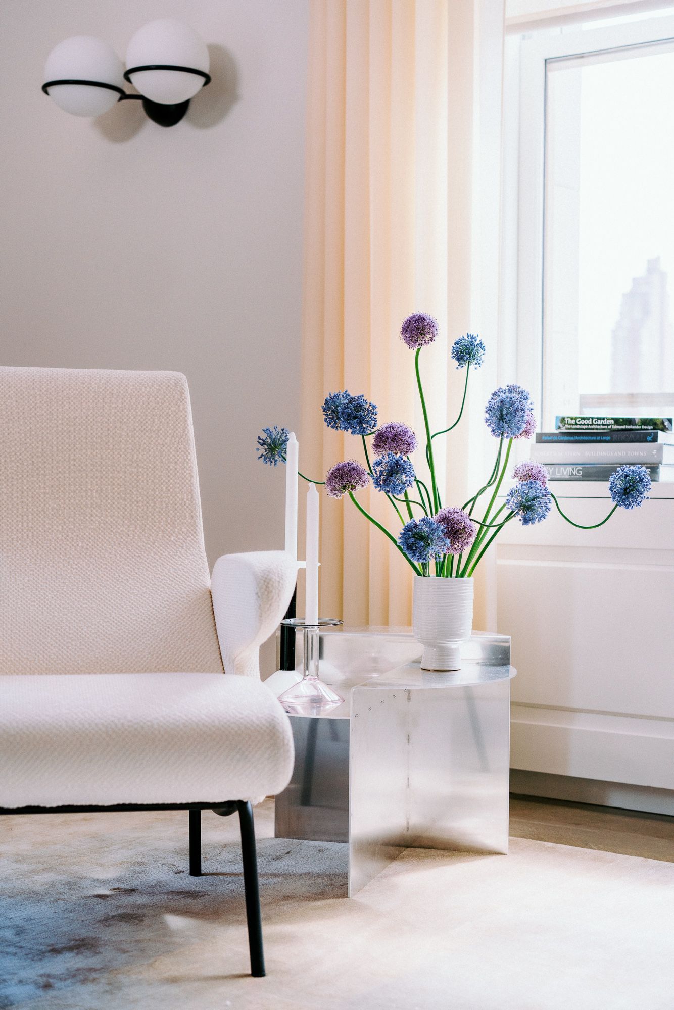 Minimalist interior with white chair and blue hydrangea flowers by window in natural light.