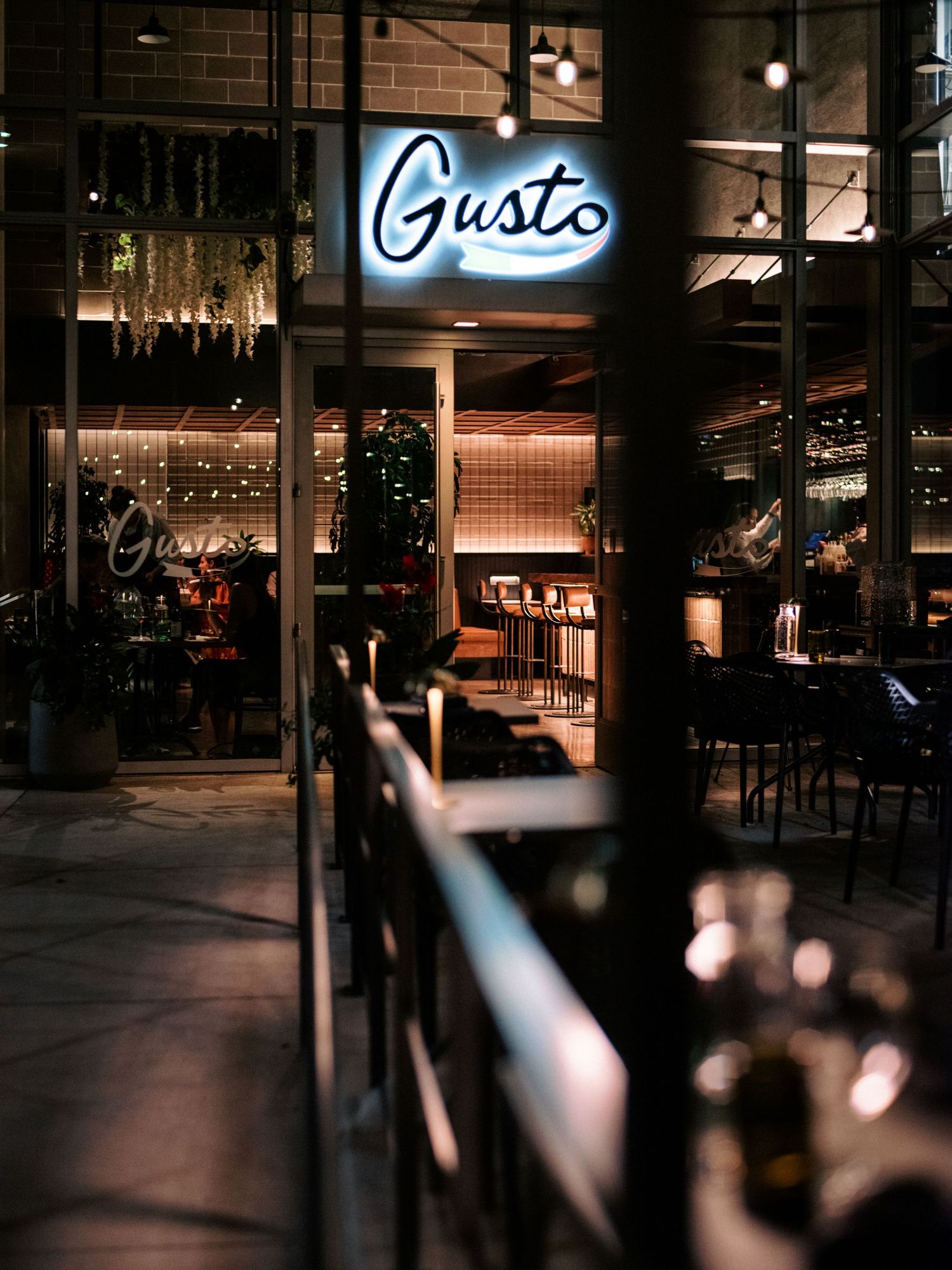 Dark atmospheric restaurant exterior with illuminated Gusto signage.