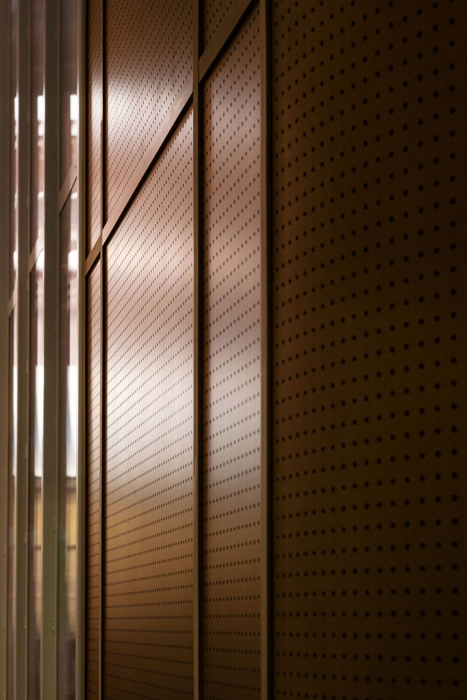 Abstract pattern of perforated metal panels with dramatic lighting and shadows.