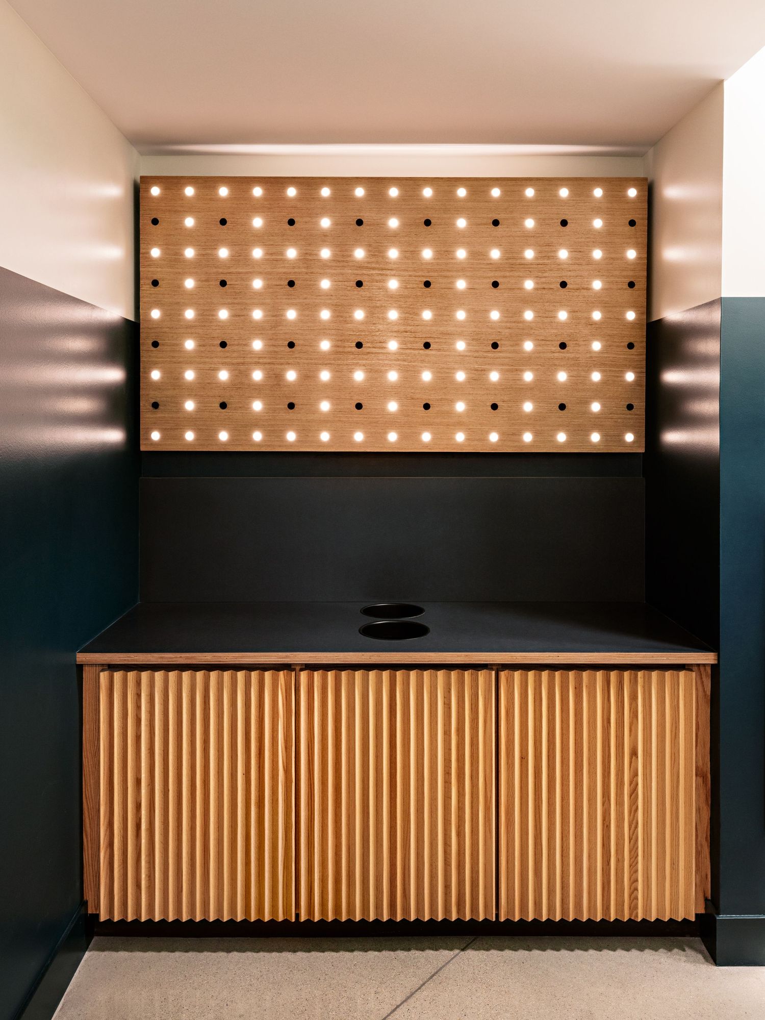Modern reception desk with wooden slats and illuminated panel above.