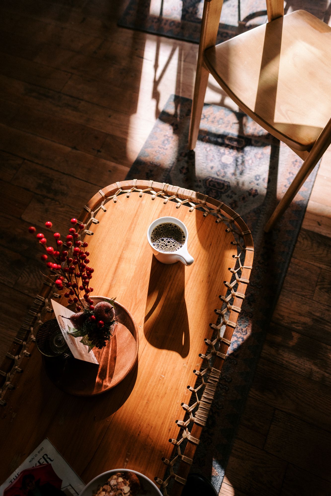 Wooden table with red berries and decorative items captured in dramatic lighting.