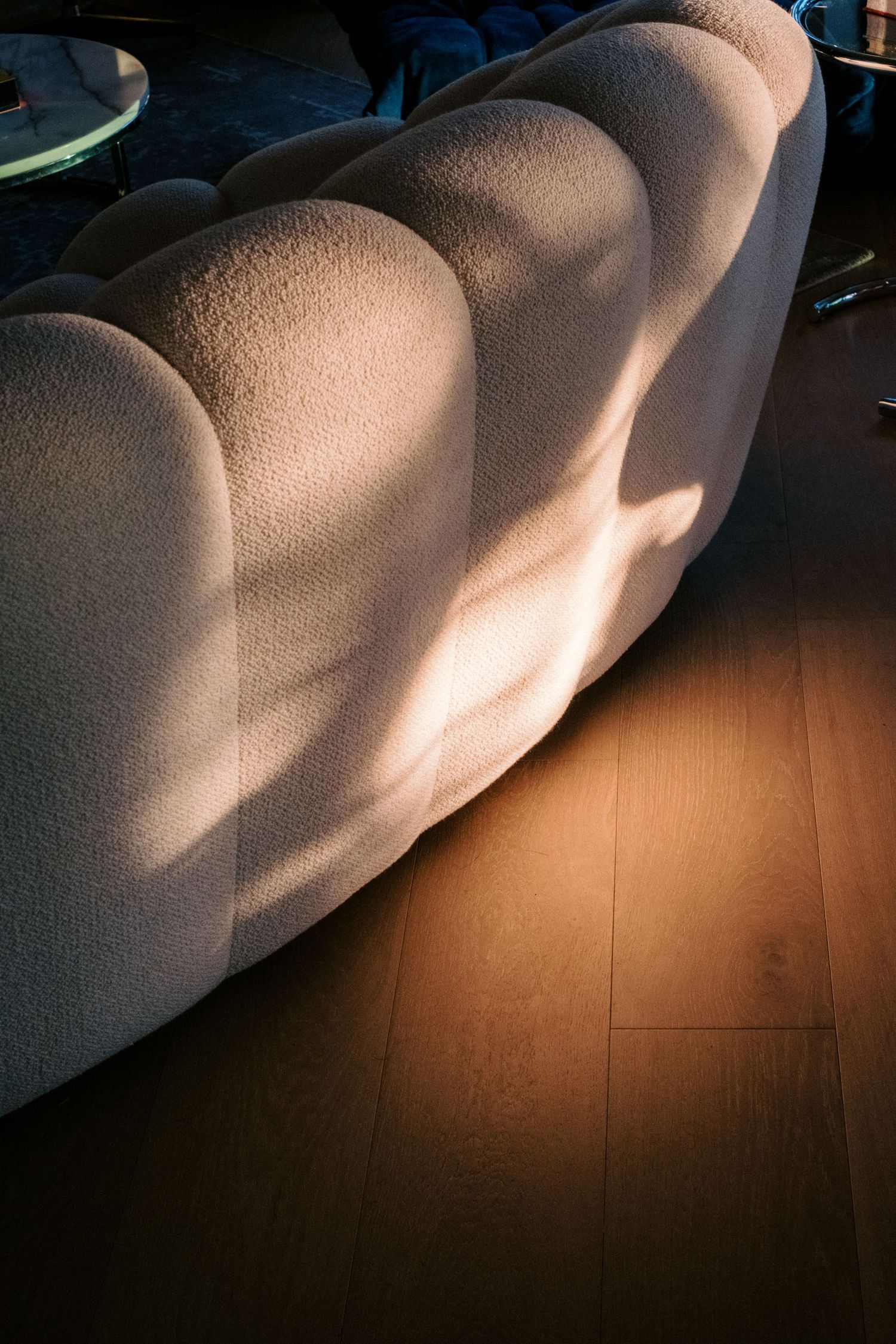Dramatic shadows cast on white upholstered furniture against wooden flooring.