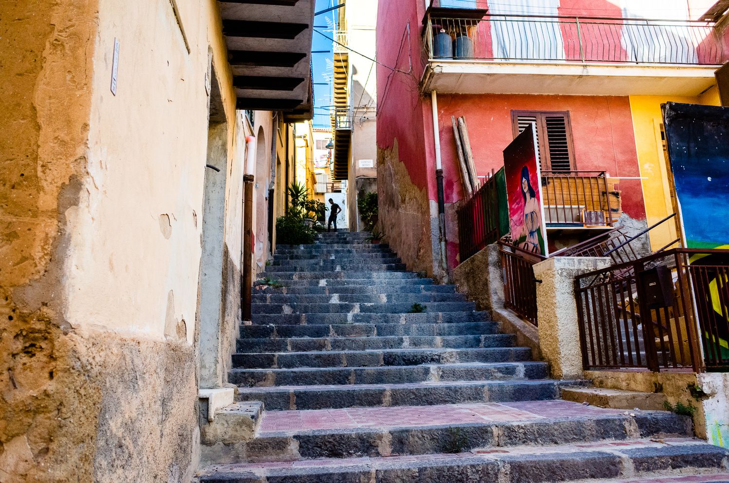 Steep stone stairway between colorful buildings in a narrow Mediterranean alley.