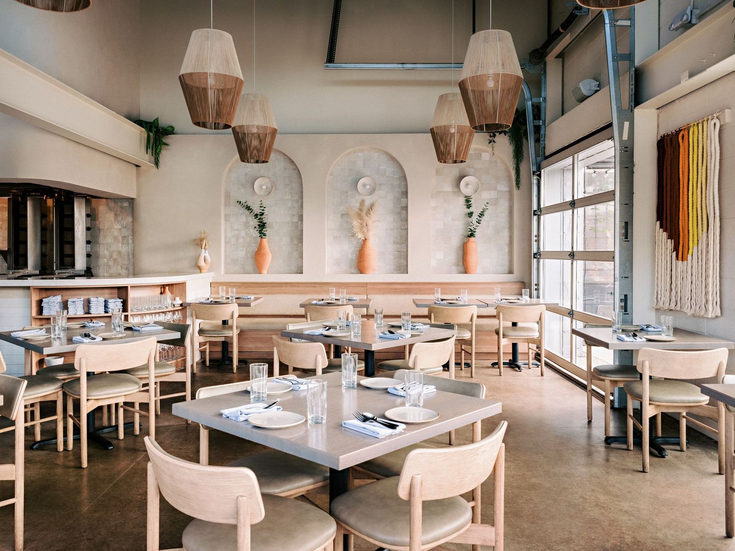 Contemporary restaurant space with white chairs, wooden tables, and pendant lighting.