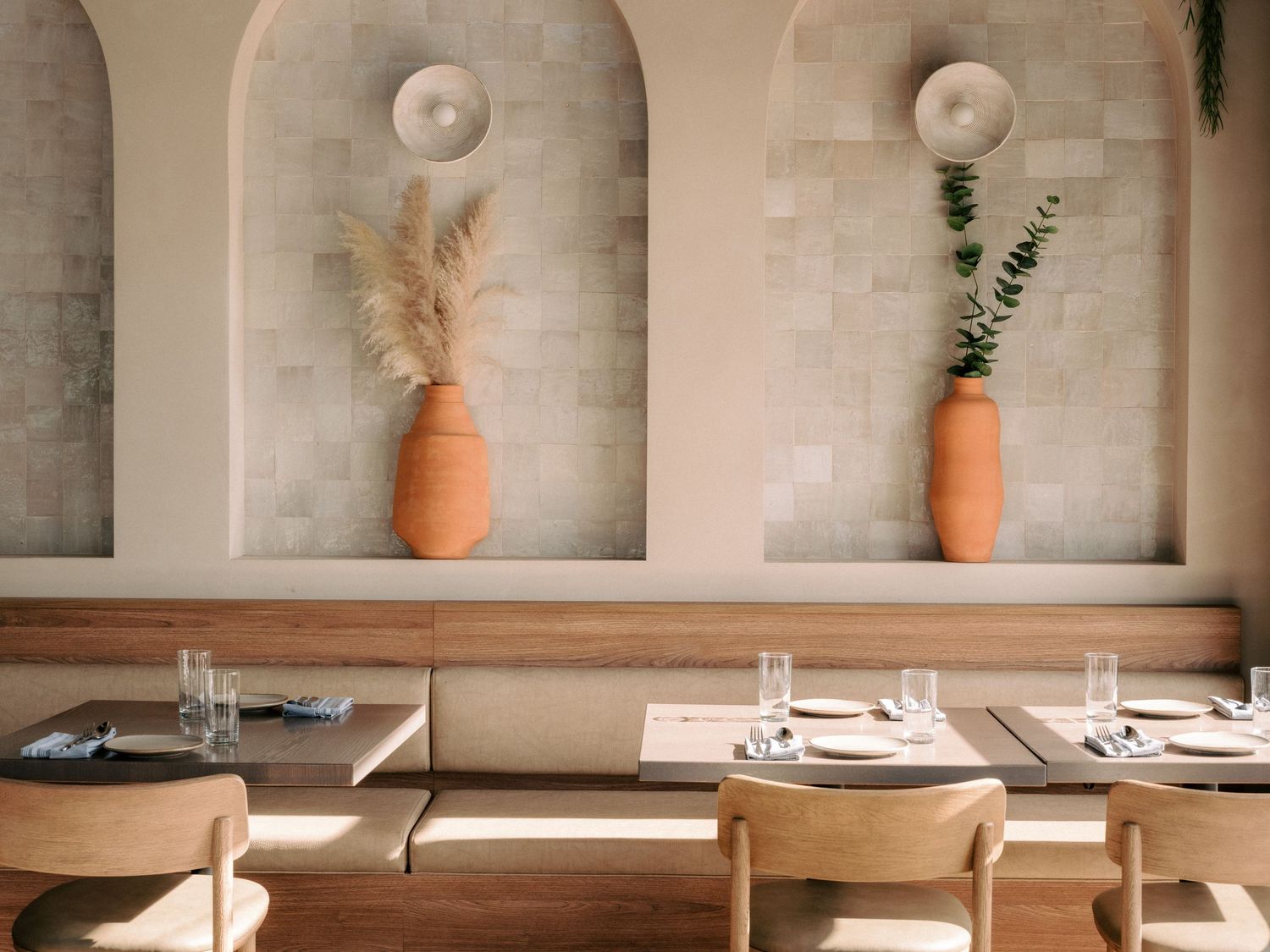 Elegant restaurant interior with arched wall niches featuring terracotta pots and minimalist decor.