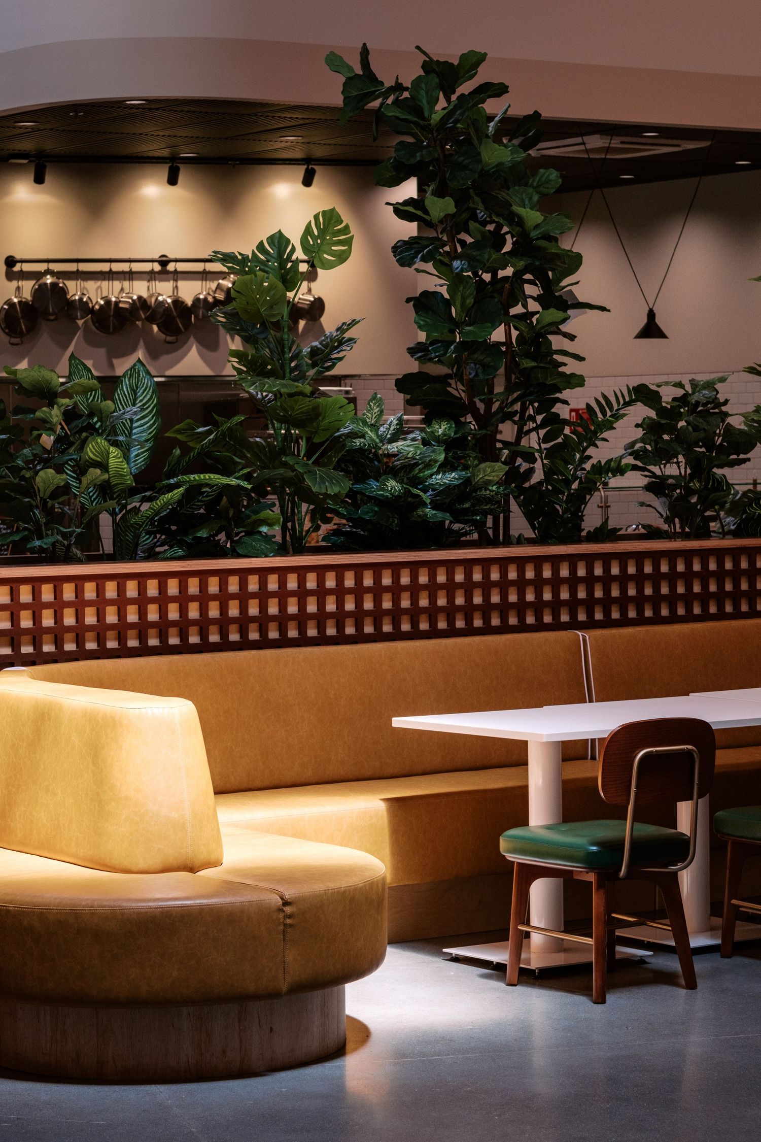 Stylish lounge area with curved yellow seating, tropical plants, and wooden lattice dividers.