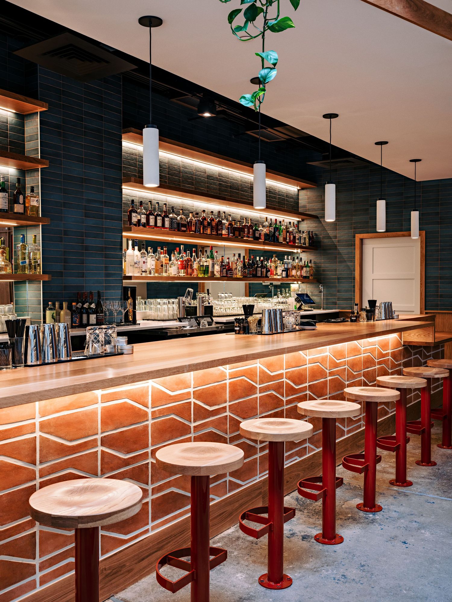 Sleek bar area featuring illuminated geometric patterns, red bar stools, and a dark blue accent wall.
