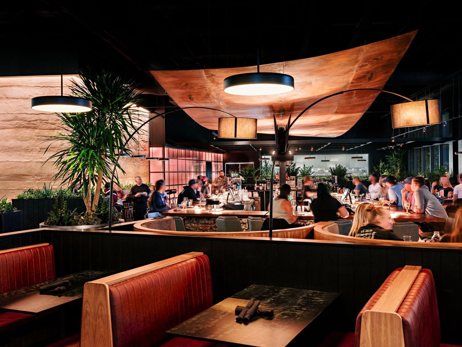 Modern restaurant interior with warm lighting and wooden ceiling panels creating an inviting ambiance.