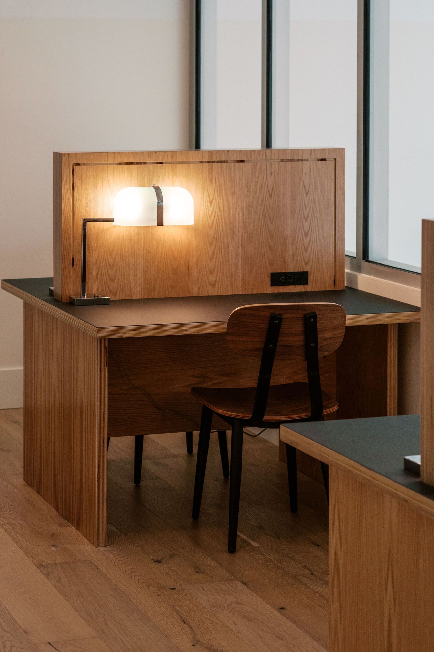 Minimalist study area with wooden desks and task lighting in a modern office setting.