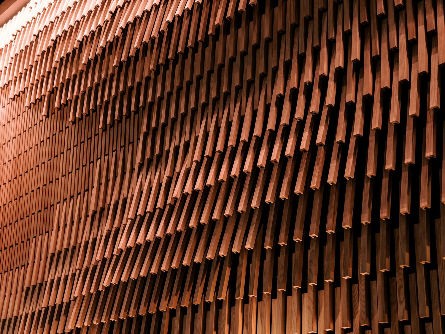Abstract pattern of wooden slats creating dimensional texture on restaurant wall.