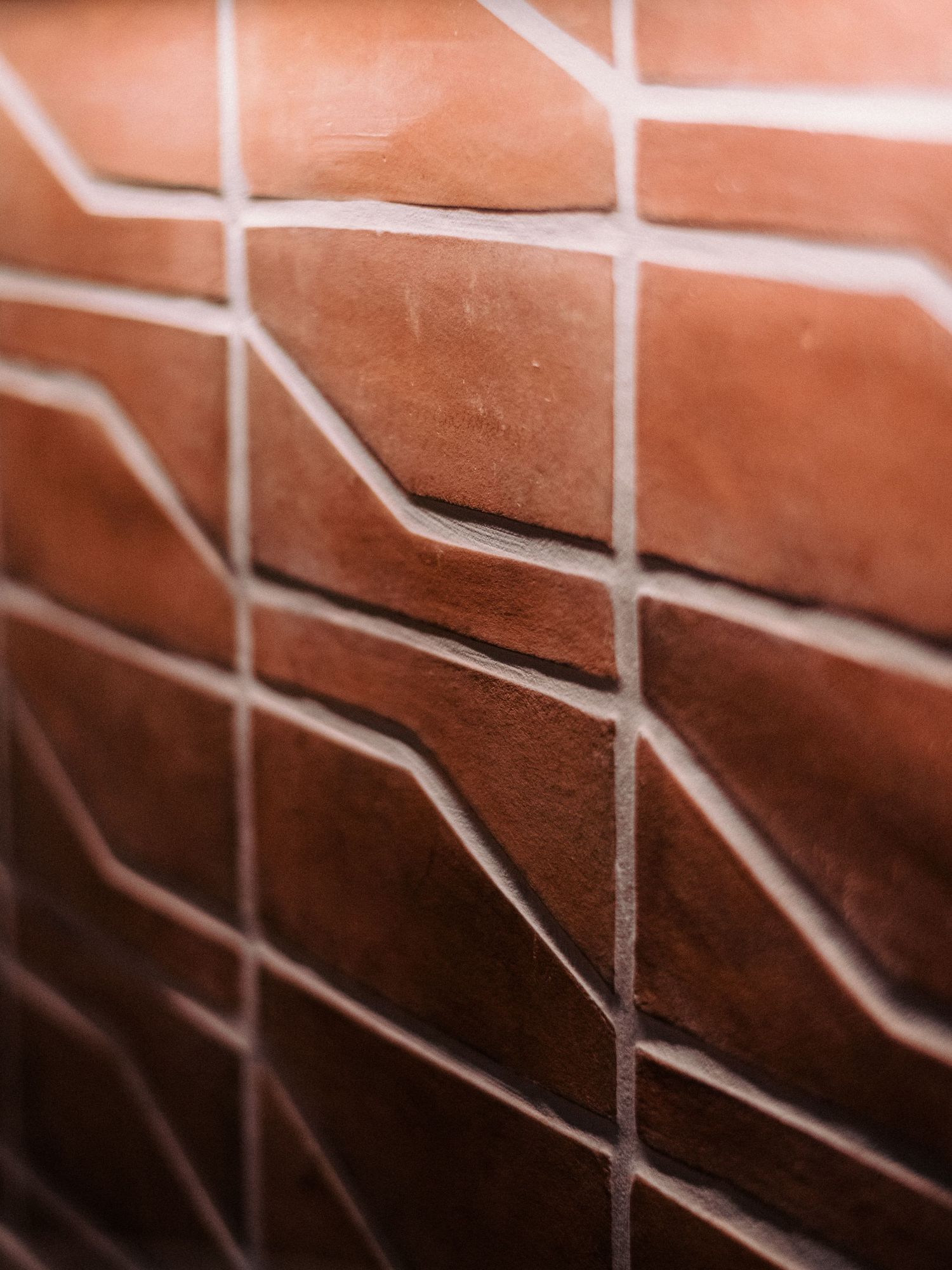 Close-up texture of terracotta colored tiles with white grout lines creating geometric patterns.